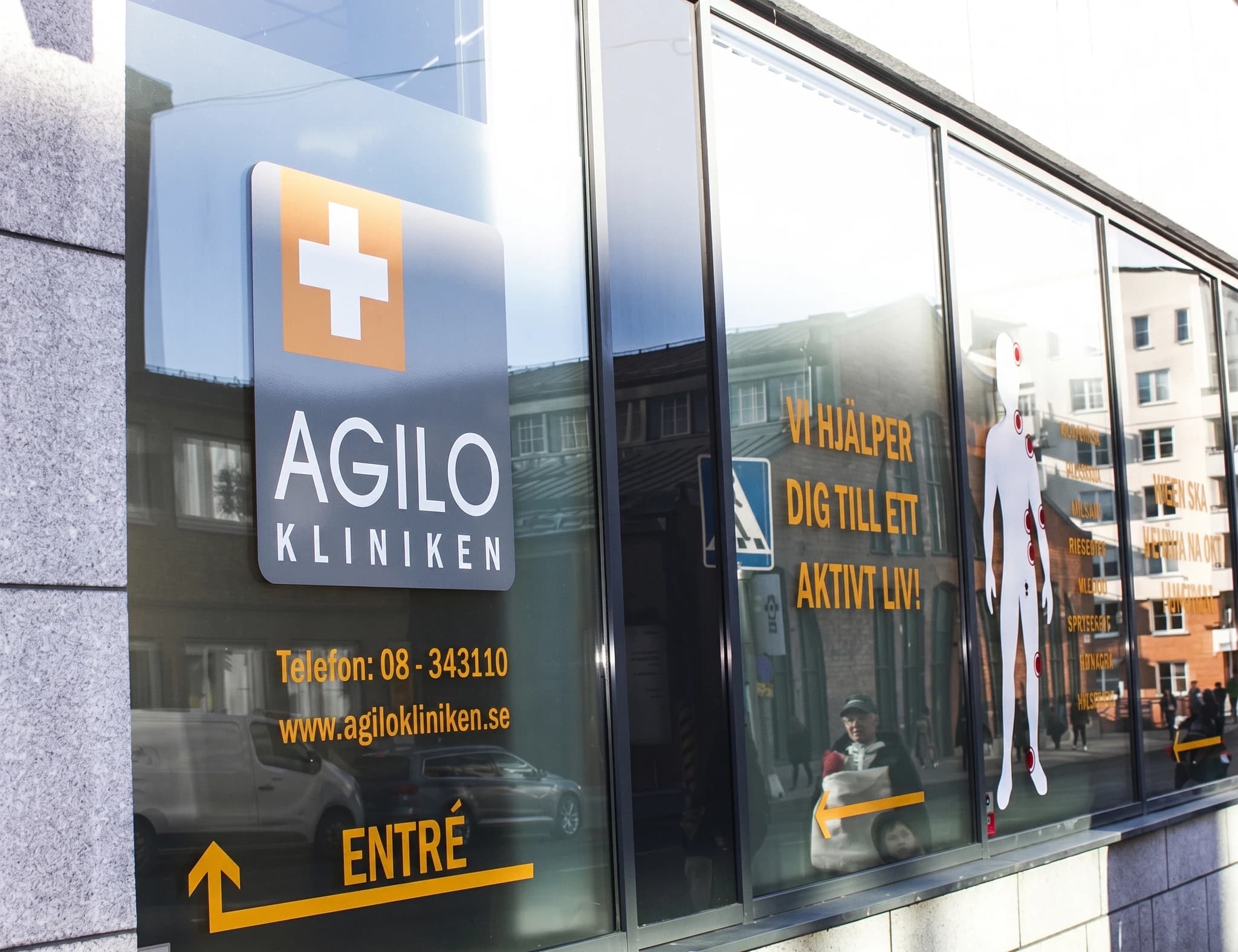 Fasadskyltning och ingång till Agilo kliniken, med en logotyp och kontaktinformation.