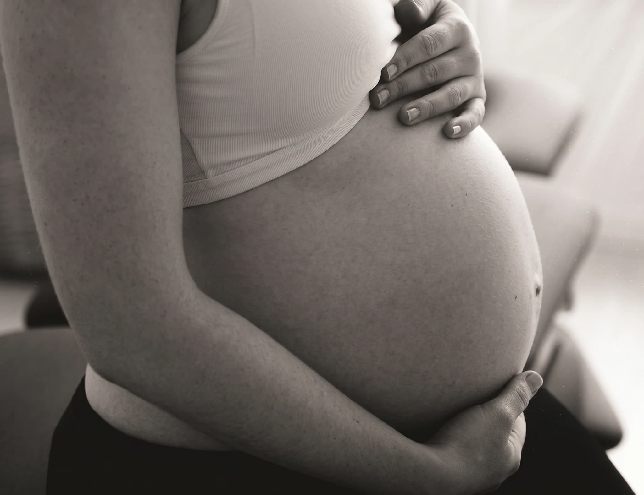 Gravid mage som hålls av händerna i en närbild.