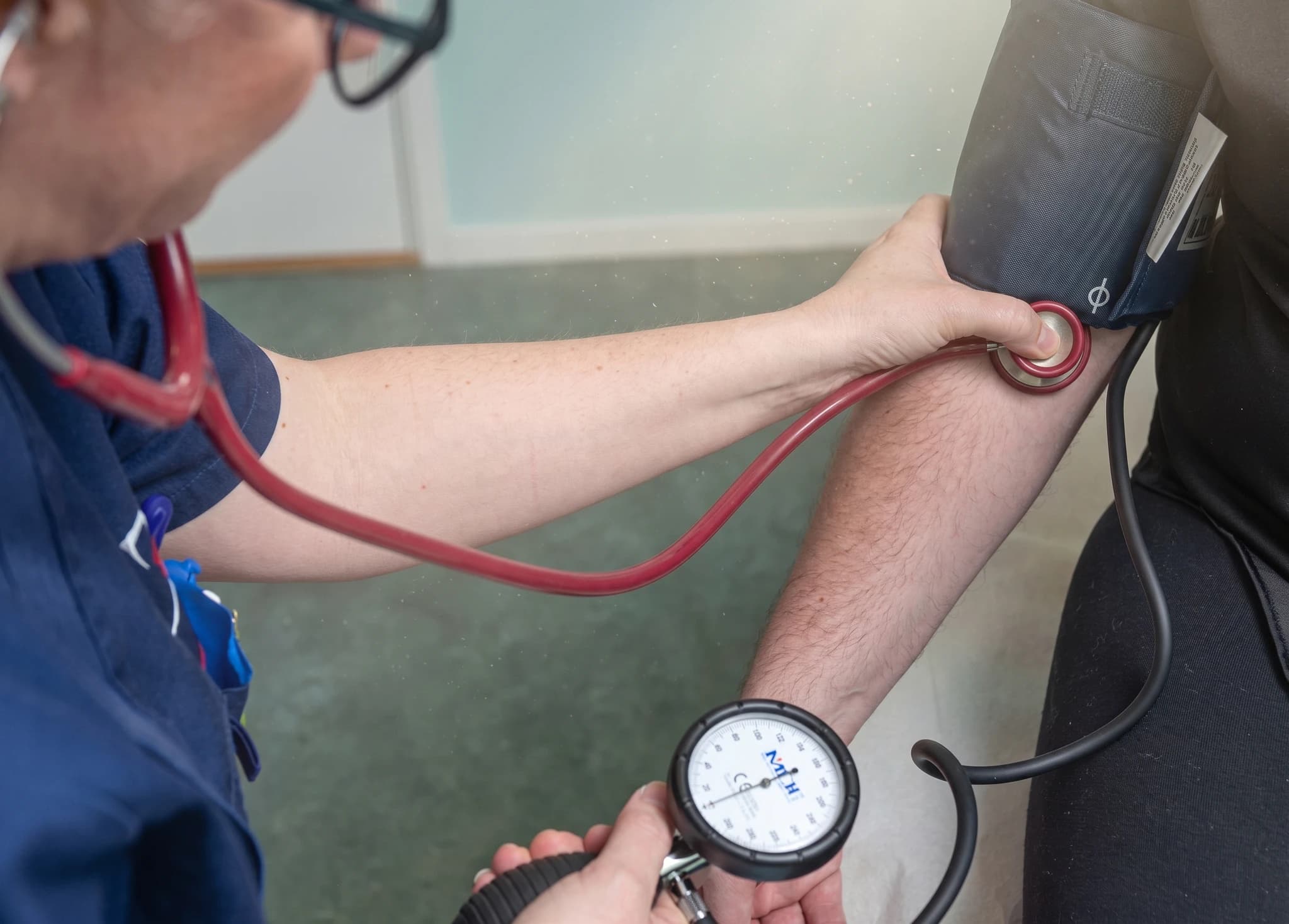 Sjuksköterska tar blodtryck på en patient med stetoskop och blodtrycksmätare.