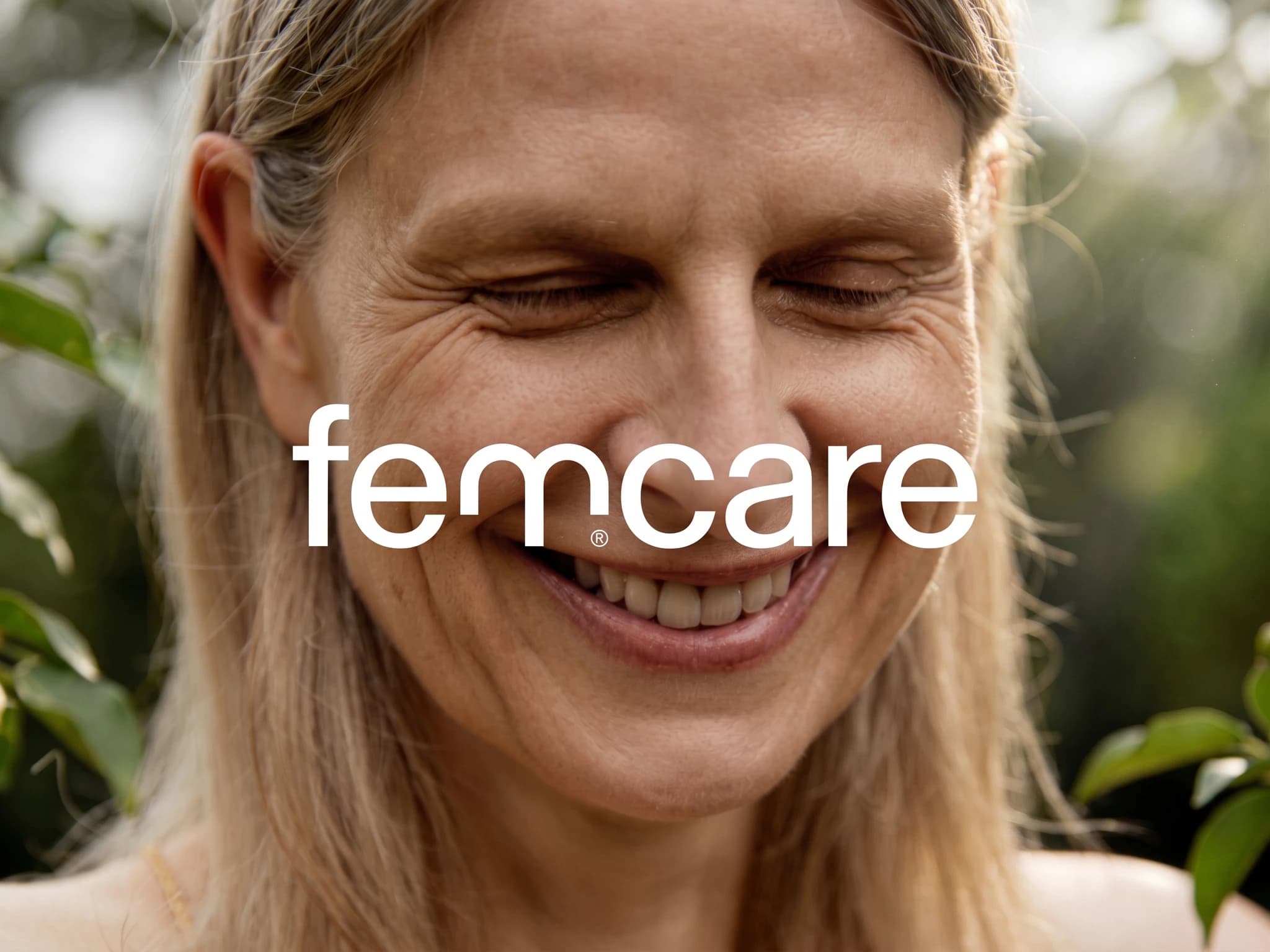 En kvinna ler med slutna ögon under texten "femcare".
