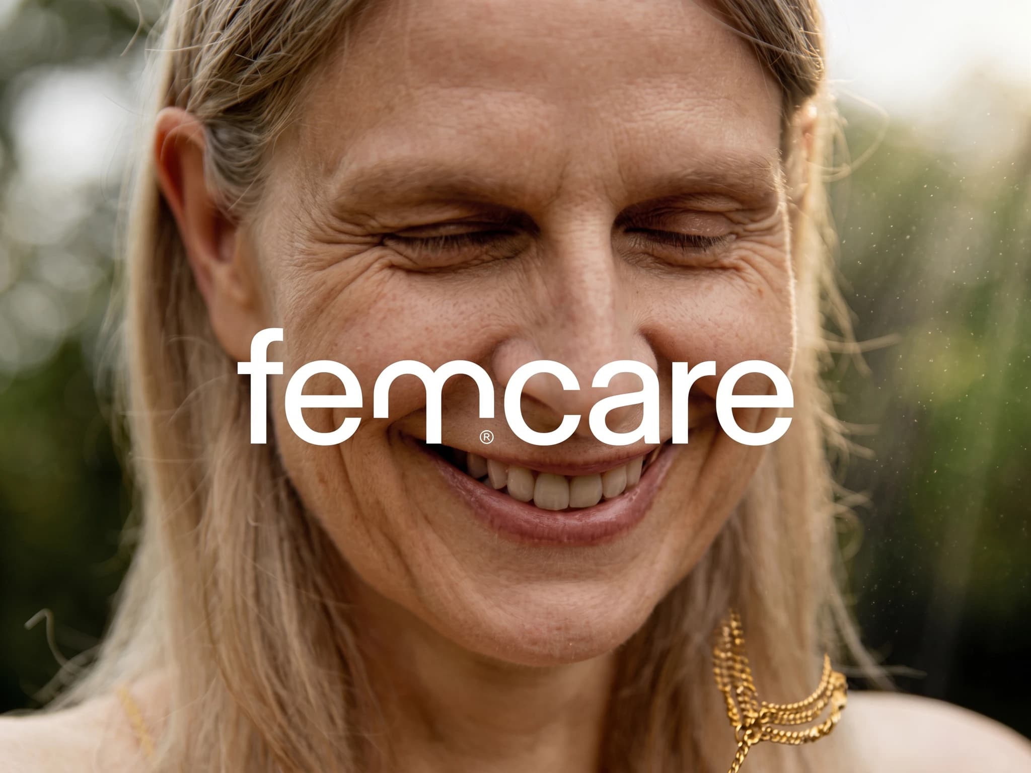 Kvinna ler med slutna ögon och logotypen "femcare" över ansiktet.