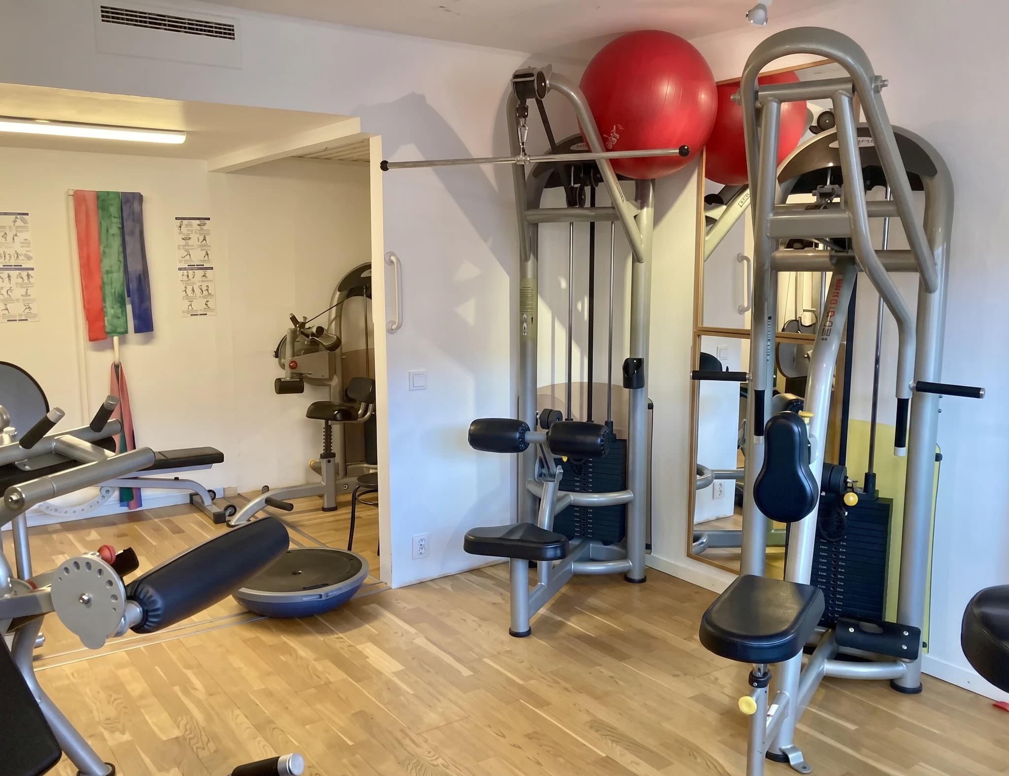 Olika gymredskap och viktskivor i ett modernt träningsrum med trägolv.