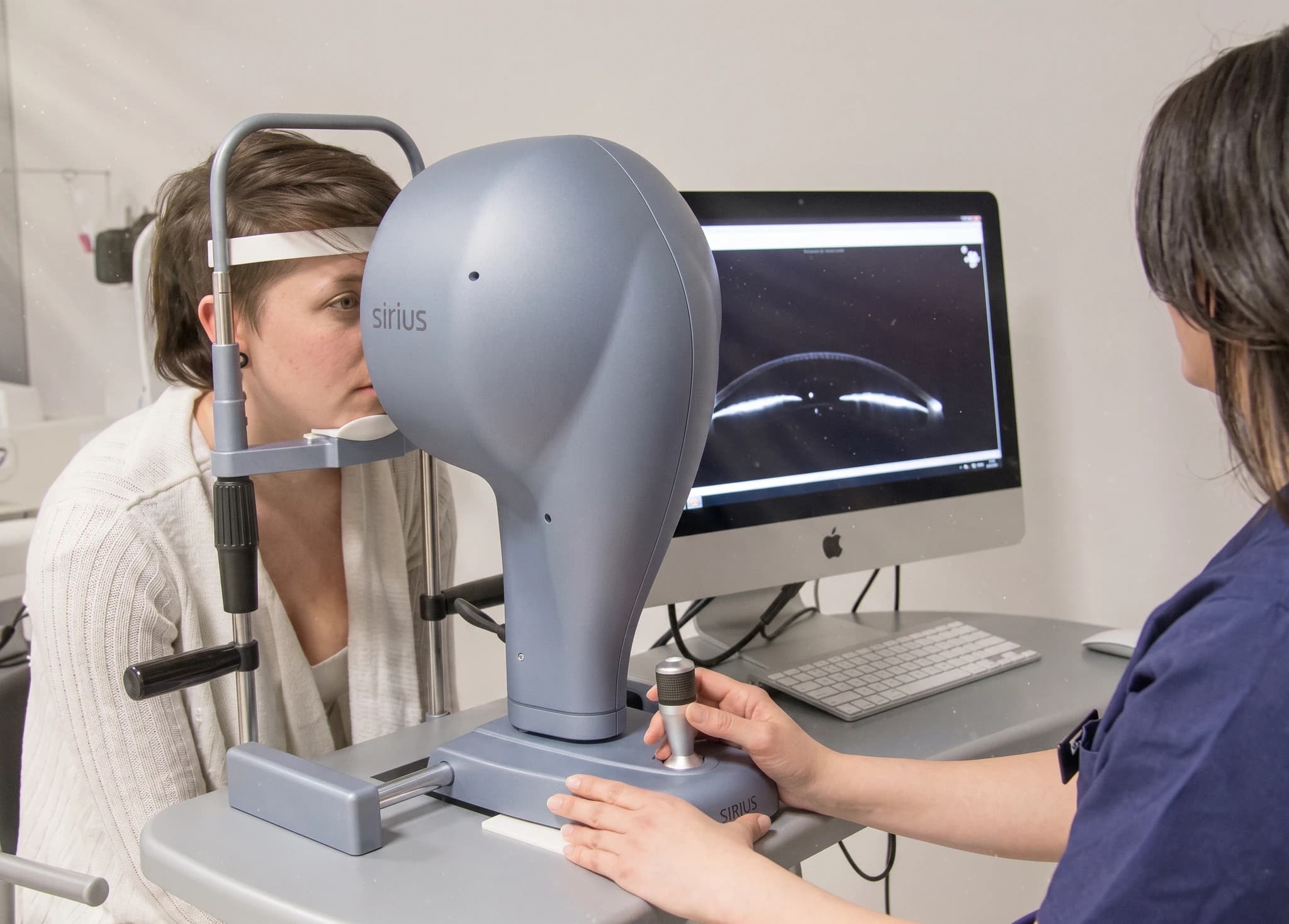 Optiker undersöker patientens öga med en modern medicinsk utrustning i ett undersökningsrum.
