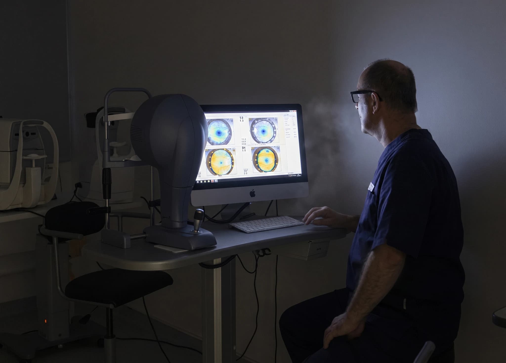 Optiker granskar ögonbilder på en datorskärm i ett undersökningsrum.