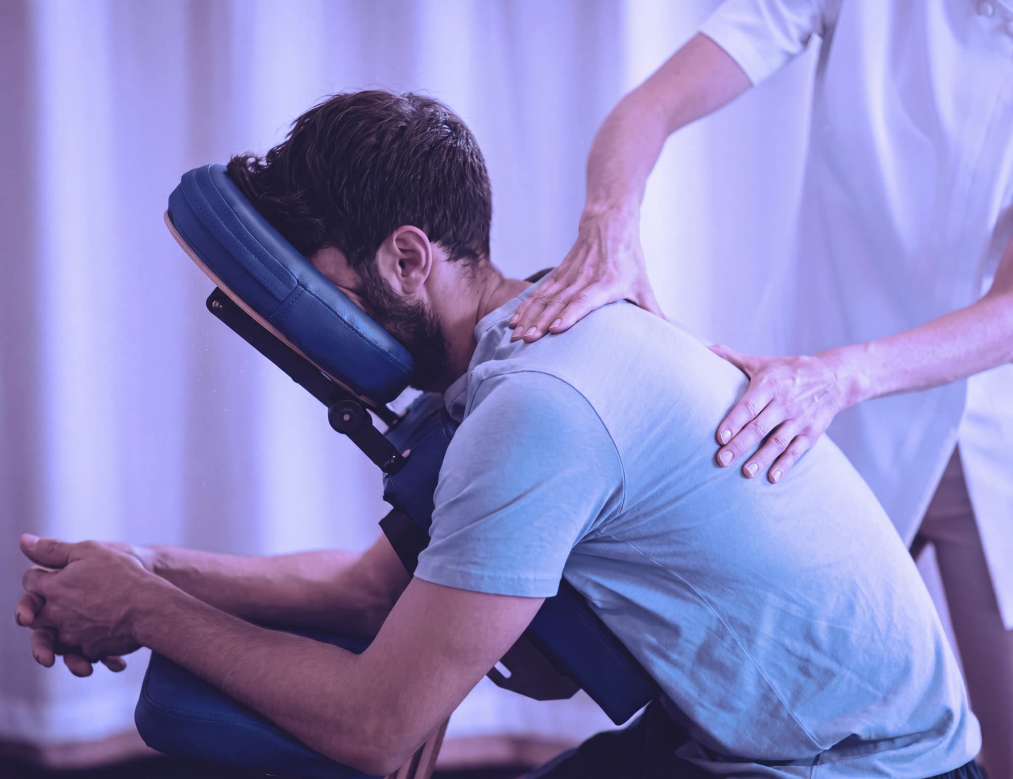 Massageterapeut som masserar en klients rygg i en massagestol