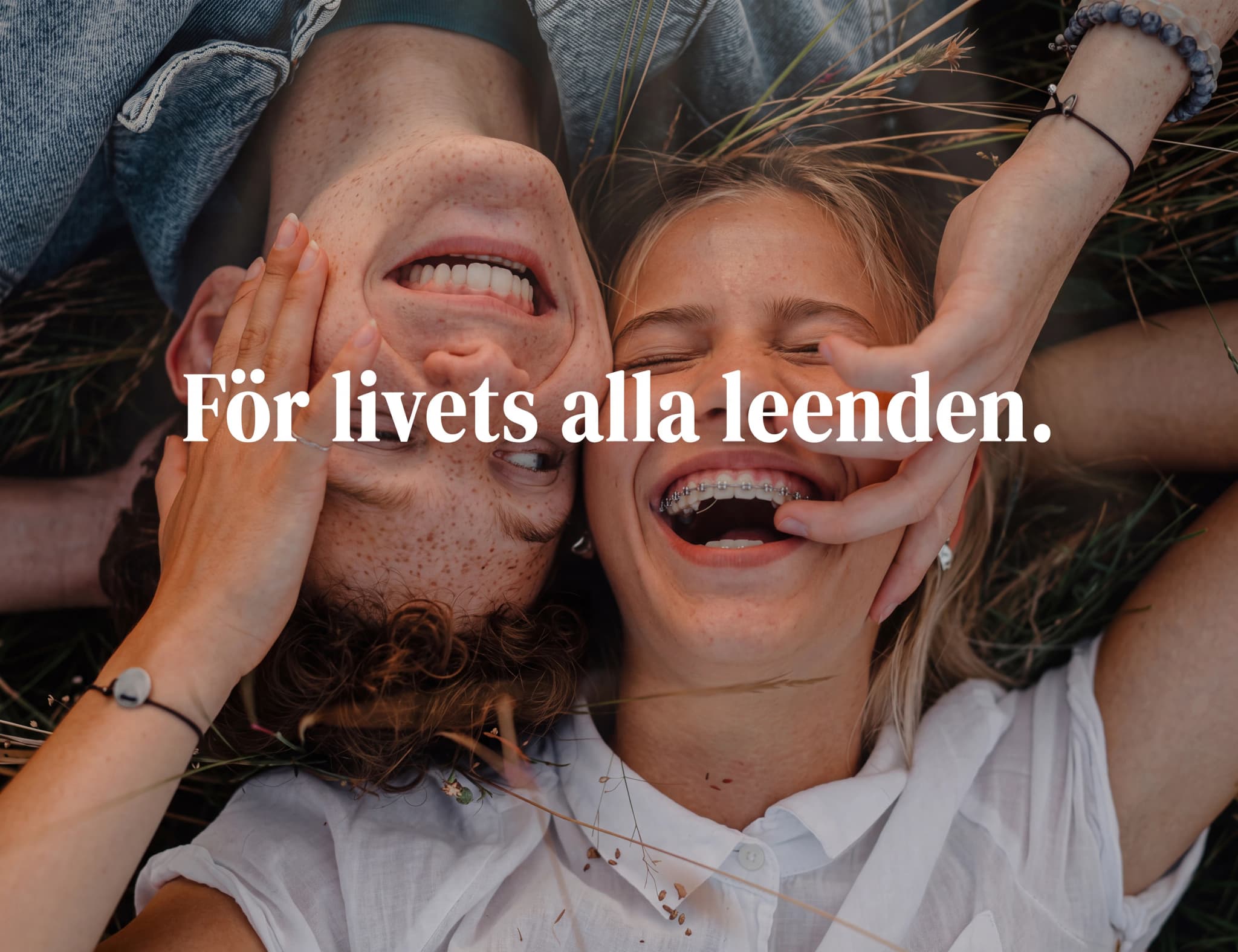 Ett ungt par ligger utomhus och skrattar, med texten "För livets alla leenden."