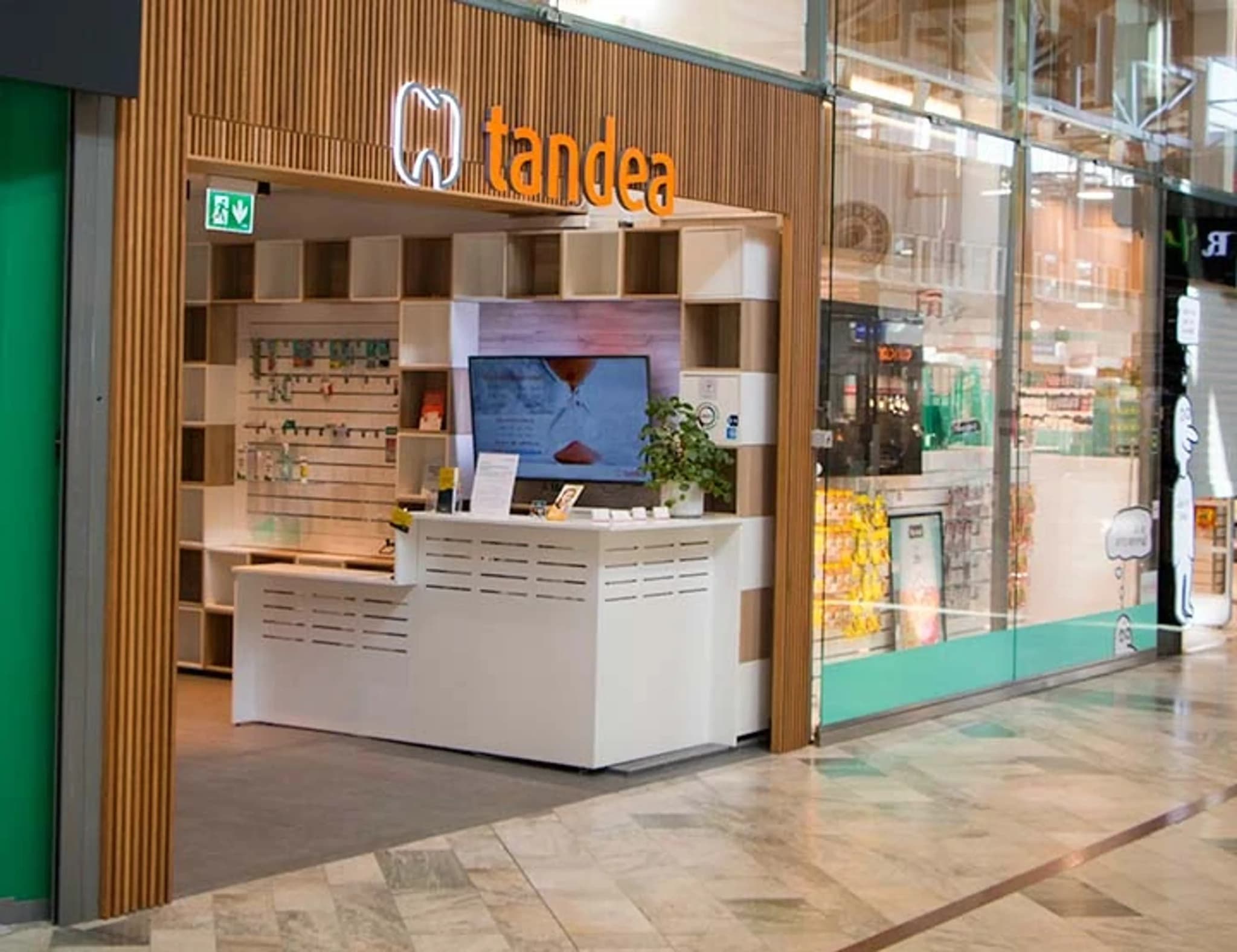 En modern reception och väntrum för tandvård med en ljus disk, hyllor med produkter och en skärm som visar ett timglas.