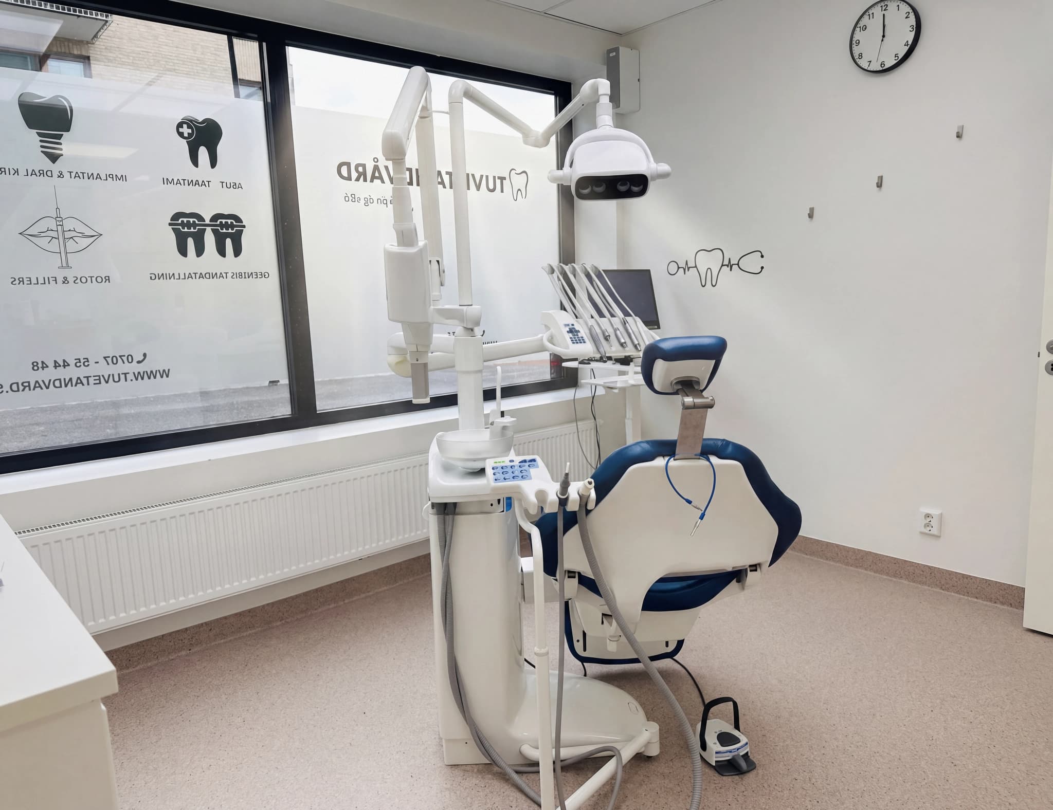 En tom tandläkarstol med medicinsk utrustning i ett ljust behandlingsrum på en tandvårdsklinik.