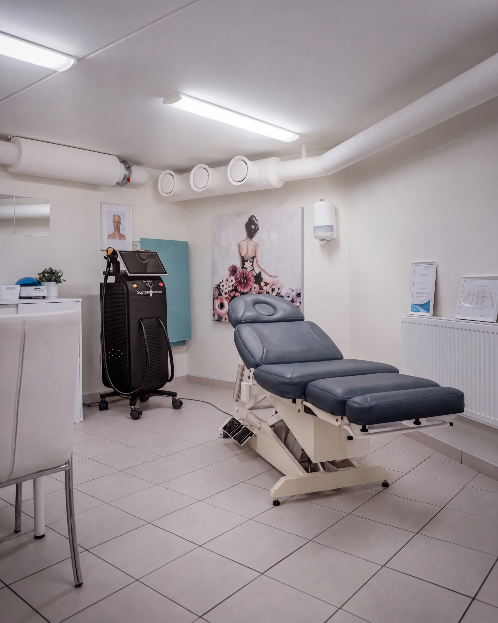 En behandlingssäng och en laserhårborttagningsmaskin i ett modernt behandlingsrum.