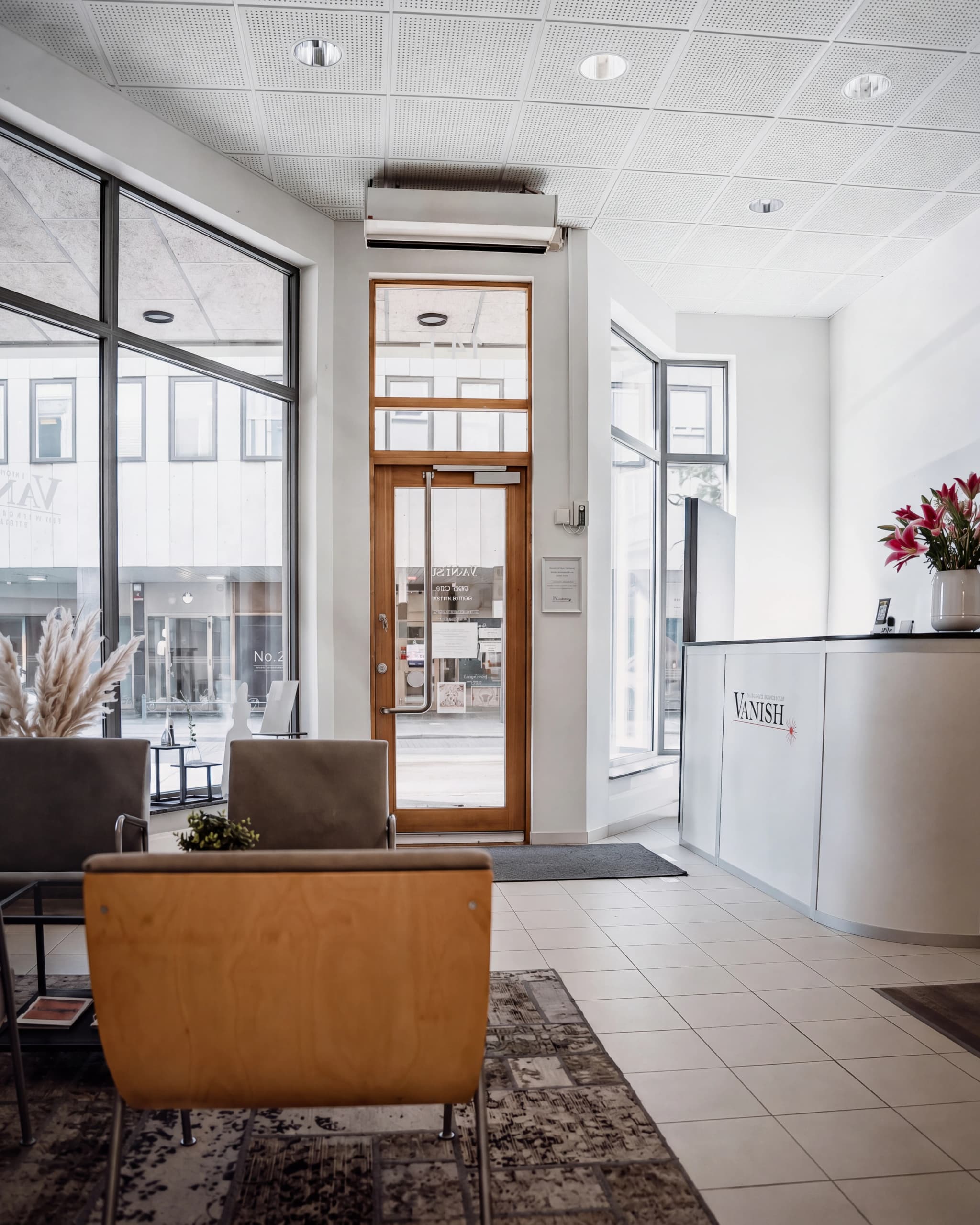 En väntsal med soffor och ett receptiondisk med 'Vanish'-logotypen i en modern klinik.