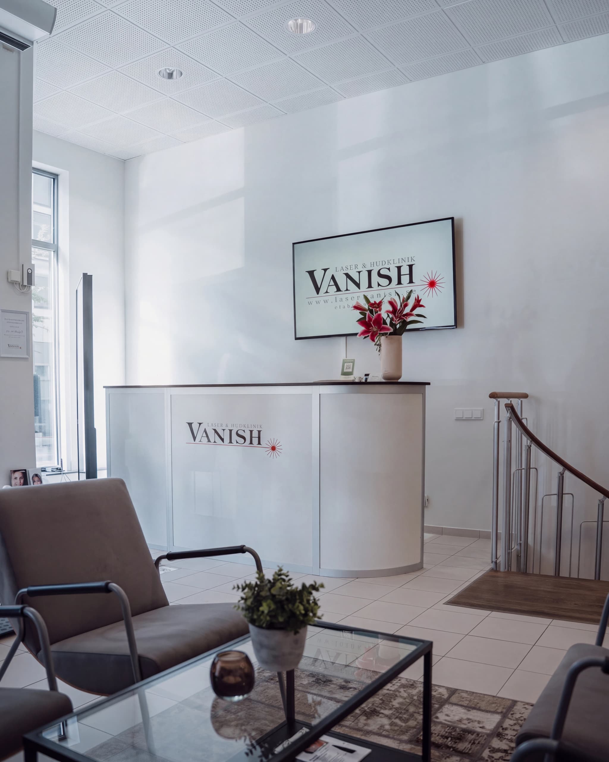En reception i en klinik med logotypen Vanish på disken och en modern stol i förgrunden.