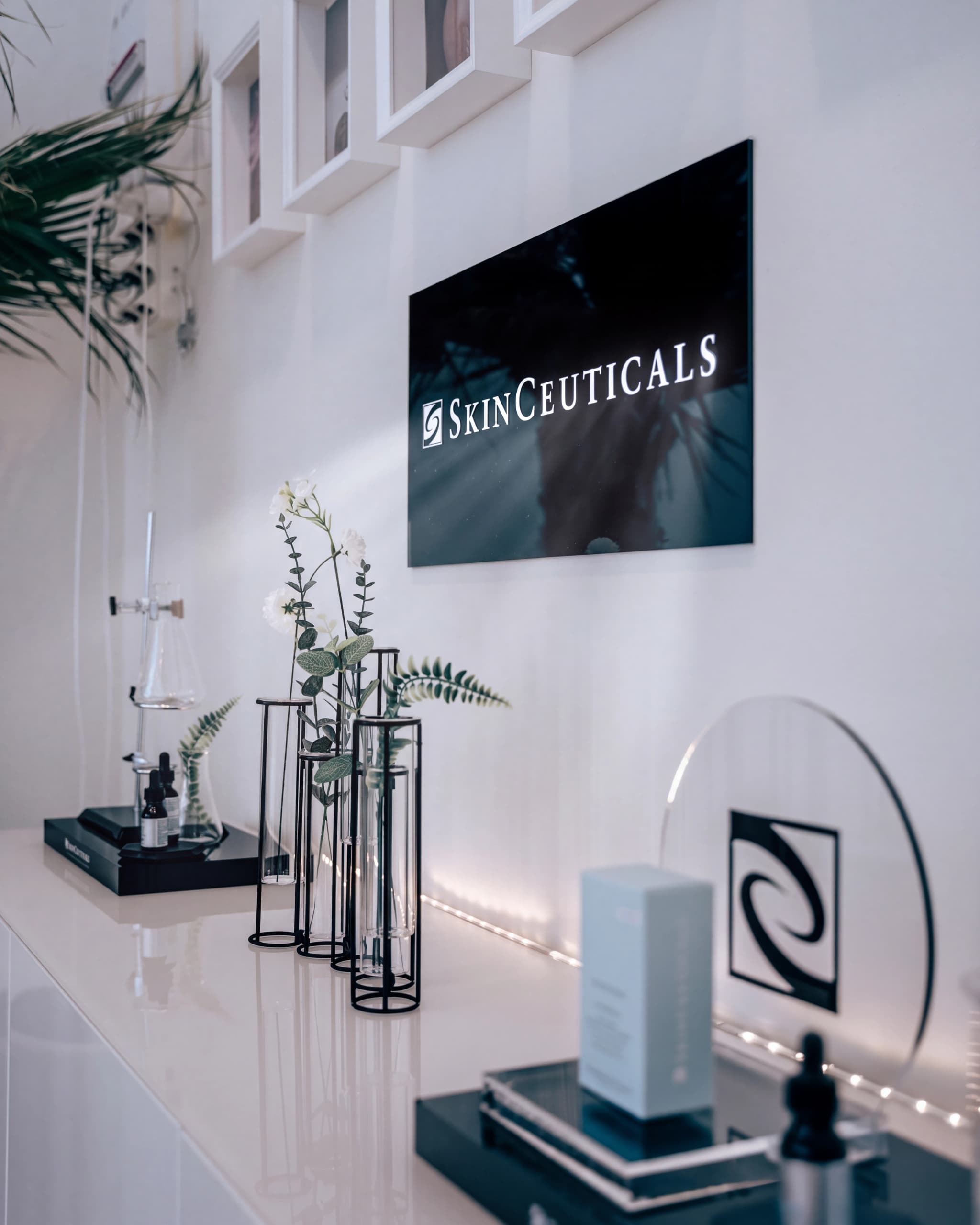 Skinceuticals-logotyp och produktförpackningar på en glansig hylla, belyst av LED-lampor.