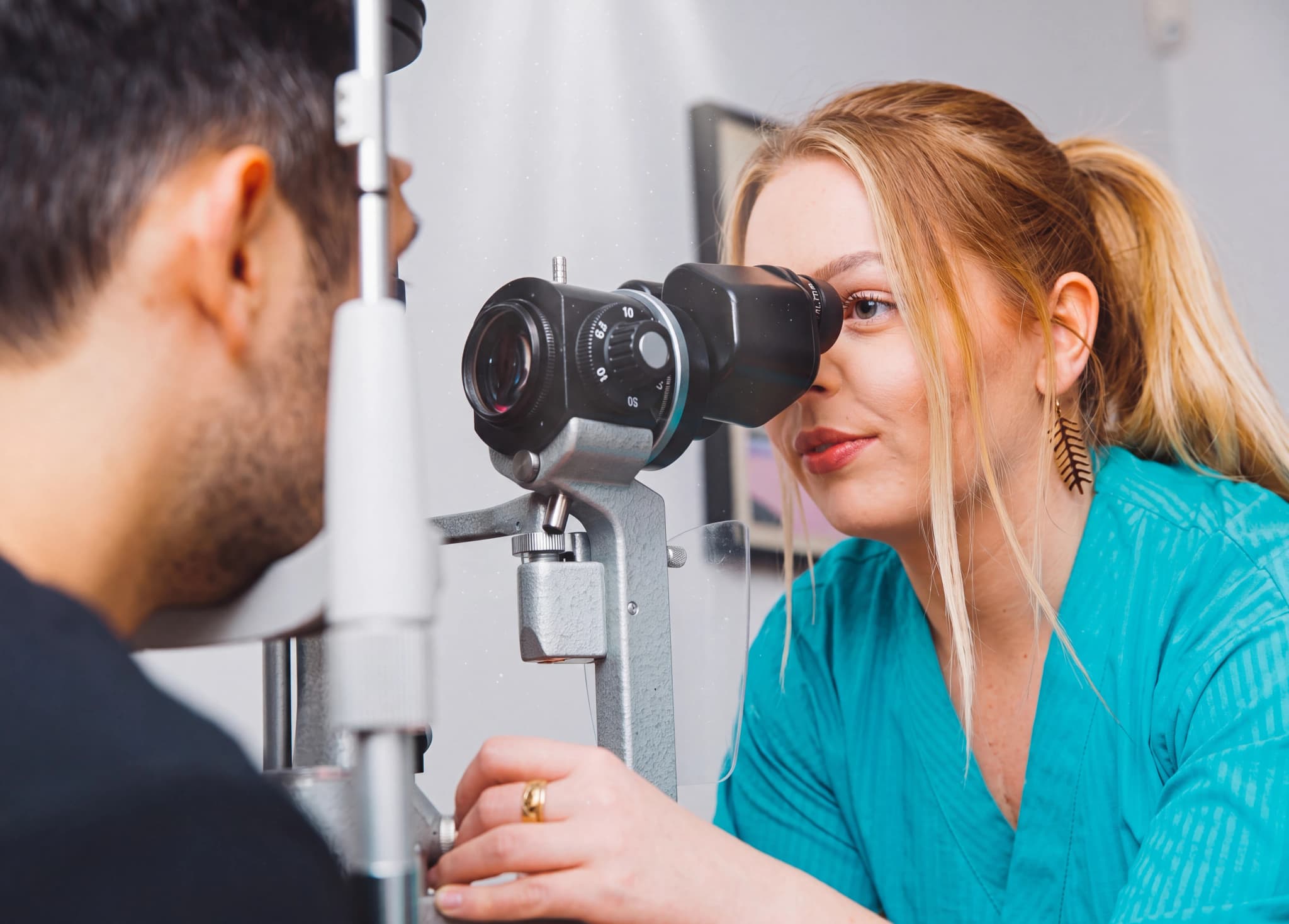 Optiker undersöker en patients öga med en spaltlampa i ett undersökningsrum.