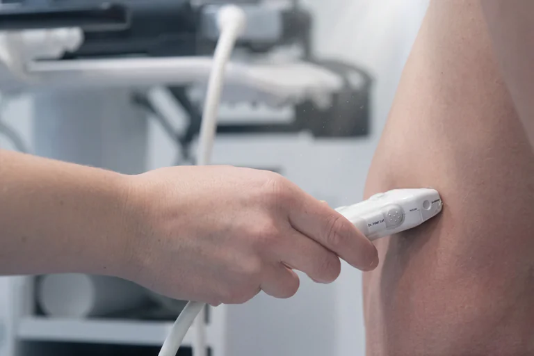 En läkare utför en ultraljudsundersökning på en arm med en ultraljudsgivare.