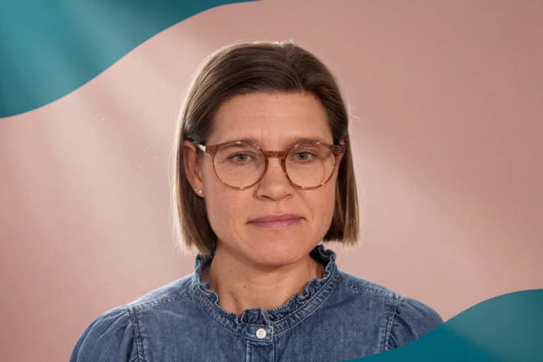 Kvinna med glasögon och en jeansskjorta framför en ljus bakgrund med dekorativa vågor.