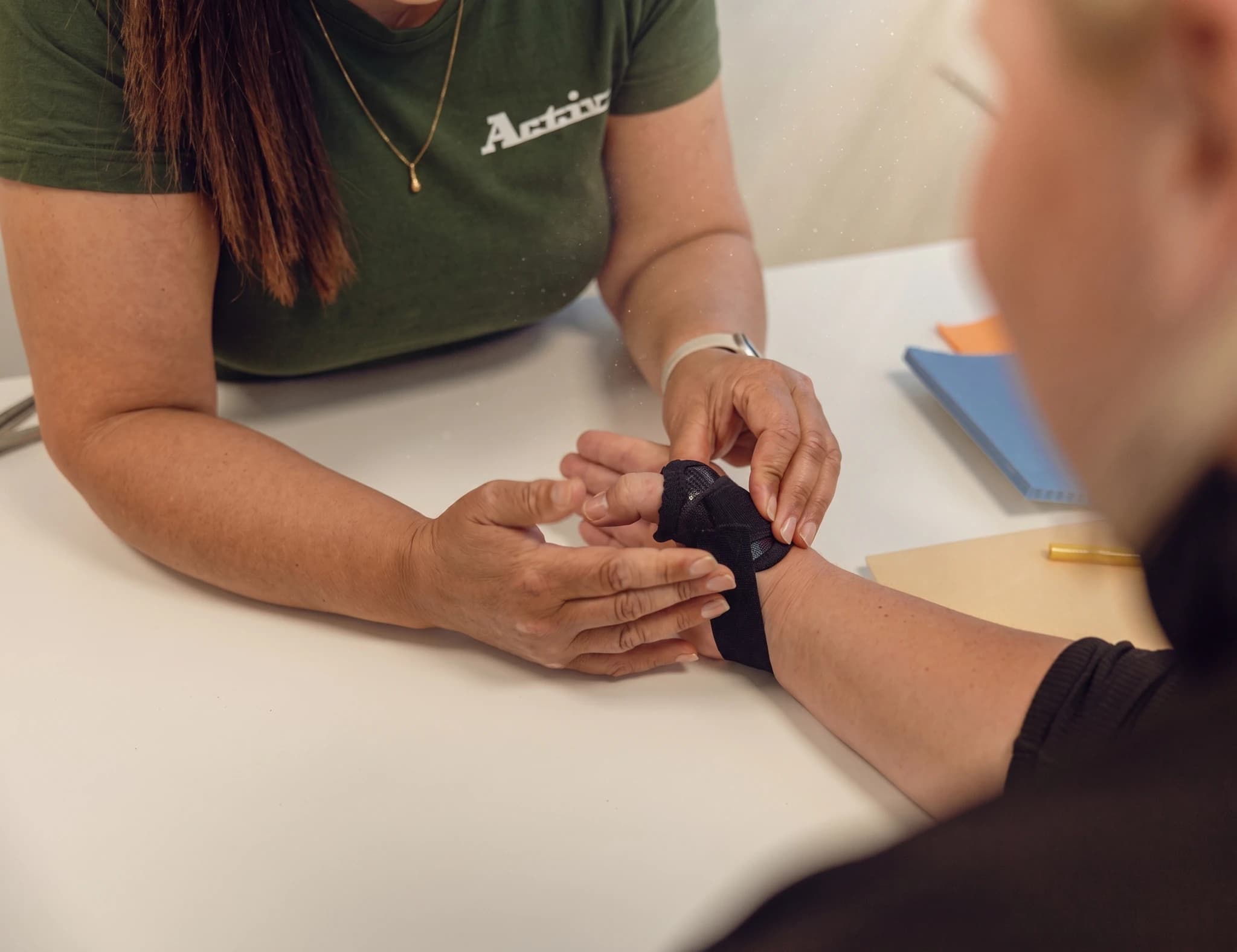 En terapeut applicerar tejp på en patients handled som en del av vårdbehandlingen.