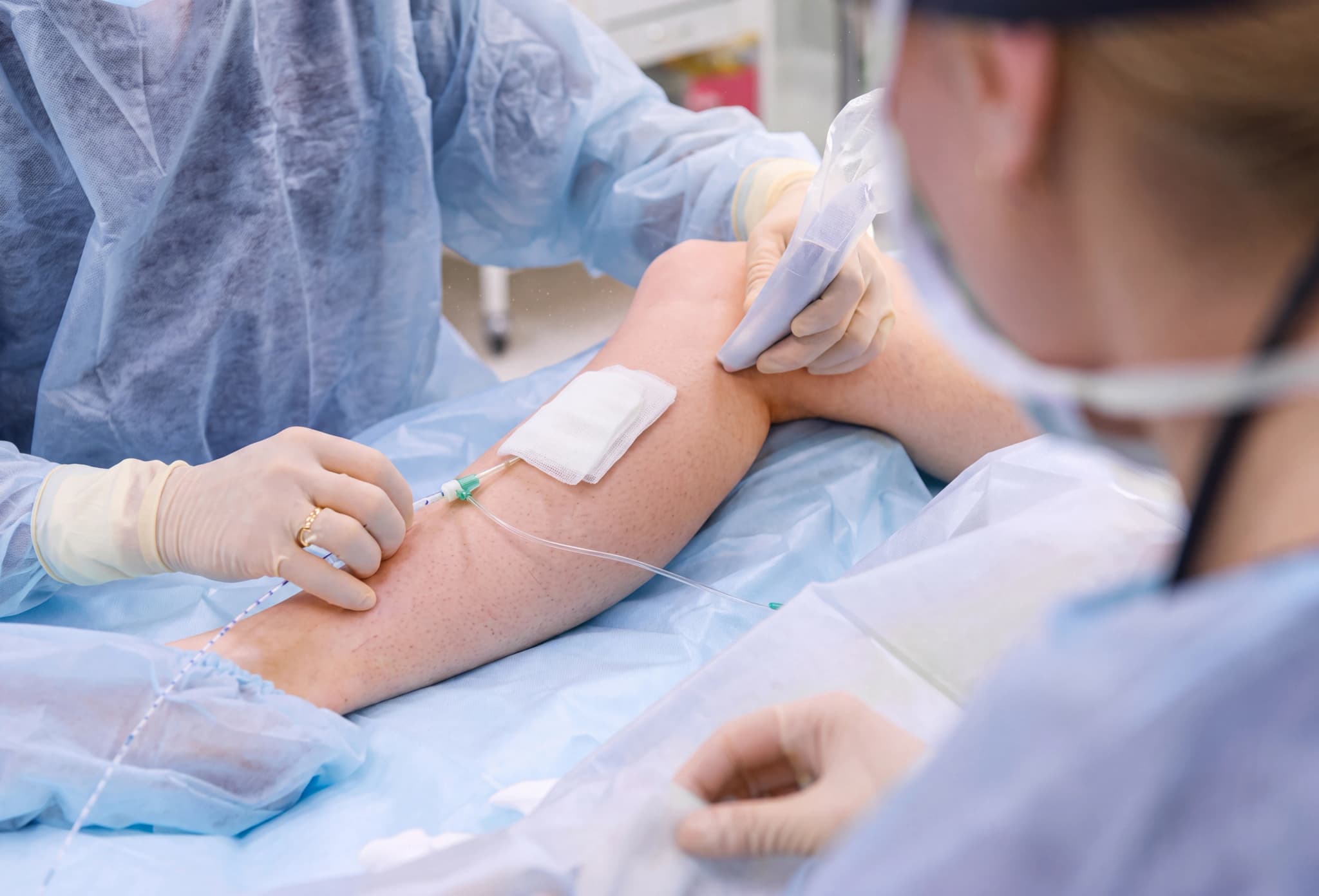 Medicinsk personal som sätter in en IV-slang i patientens arm under en medicinsk procedur.
