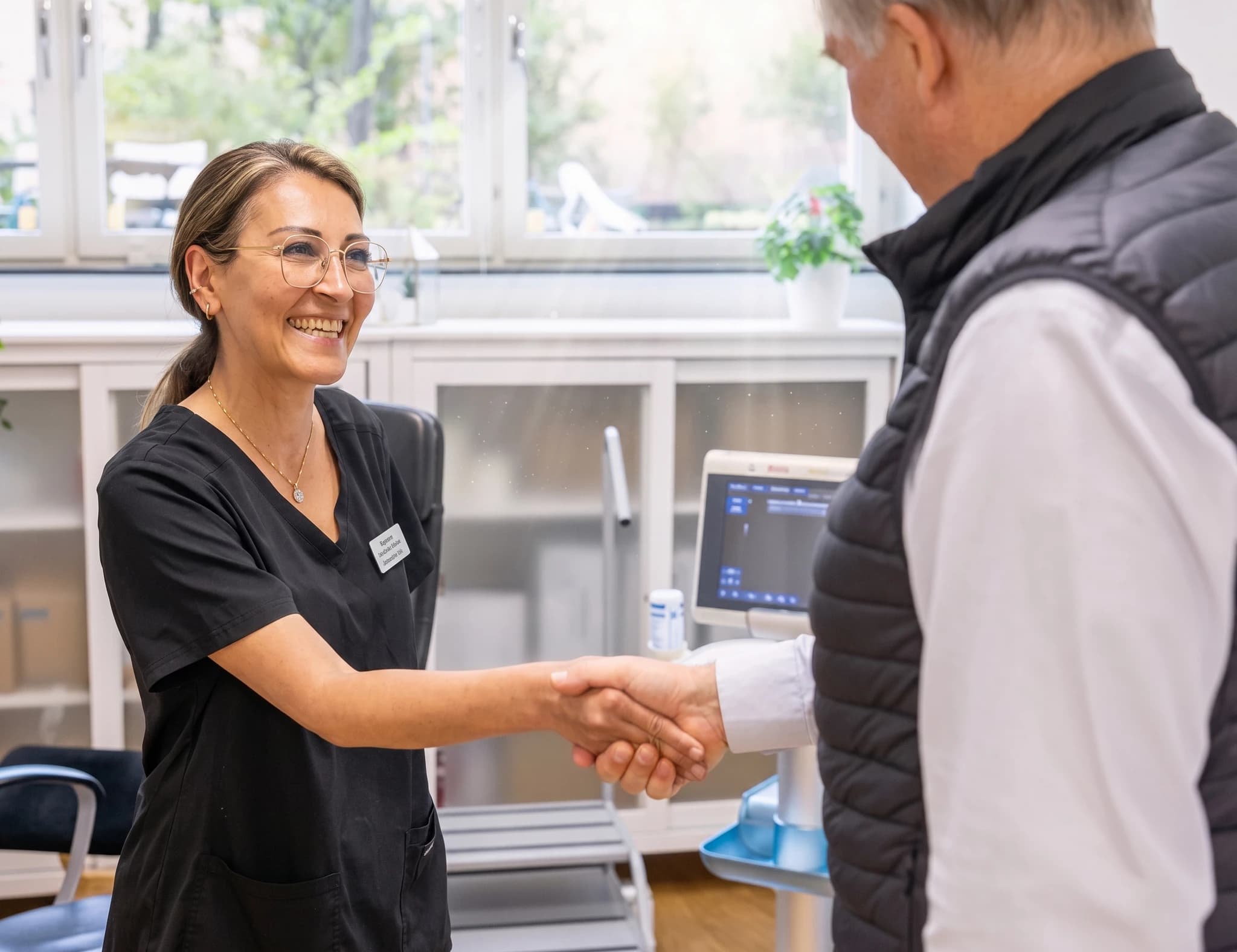 Läkare skakar hand med patient i ett undersökningsrum