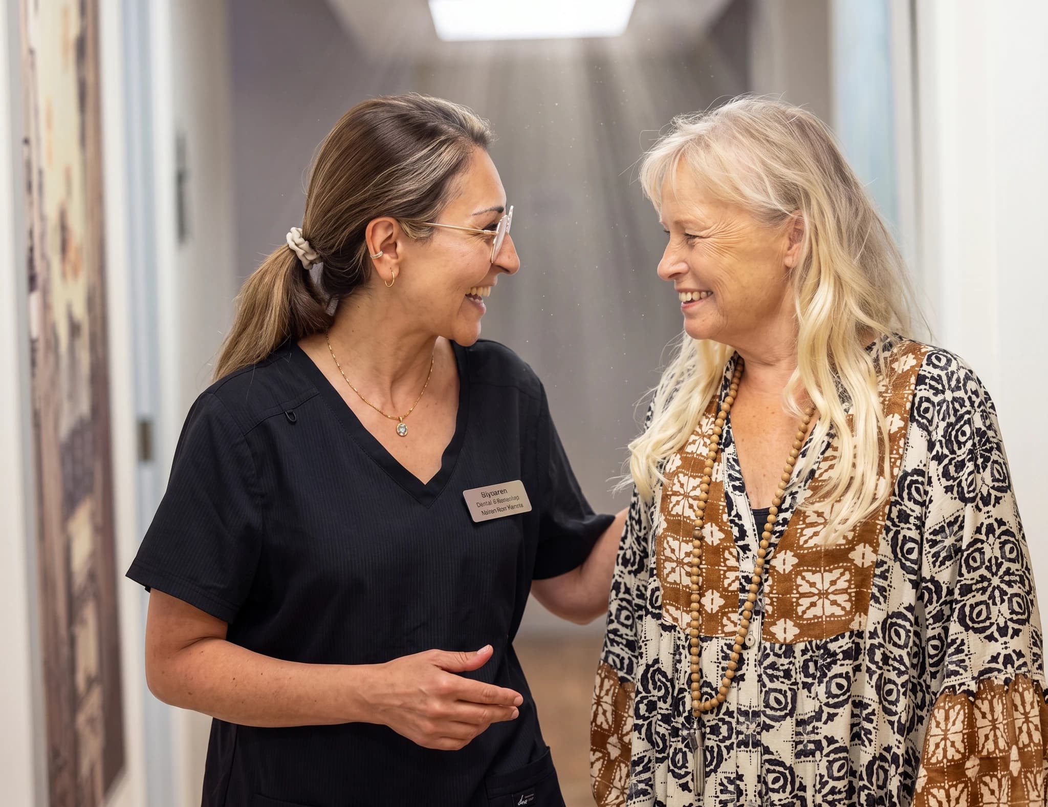 Klinikpersonal pratar med patient under ett samtal i en korridor.