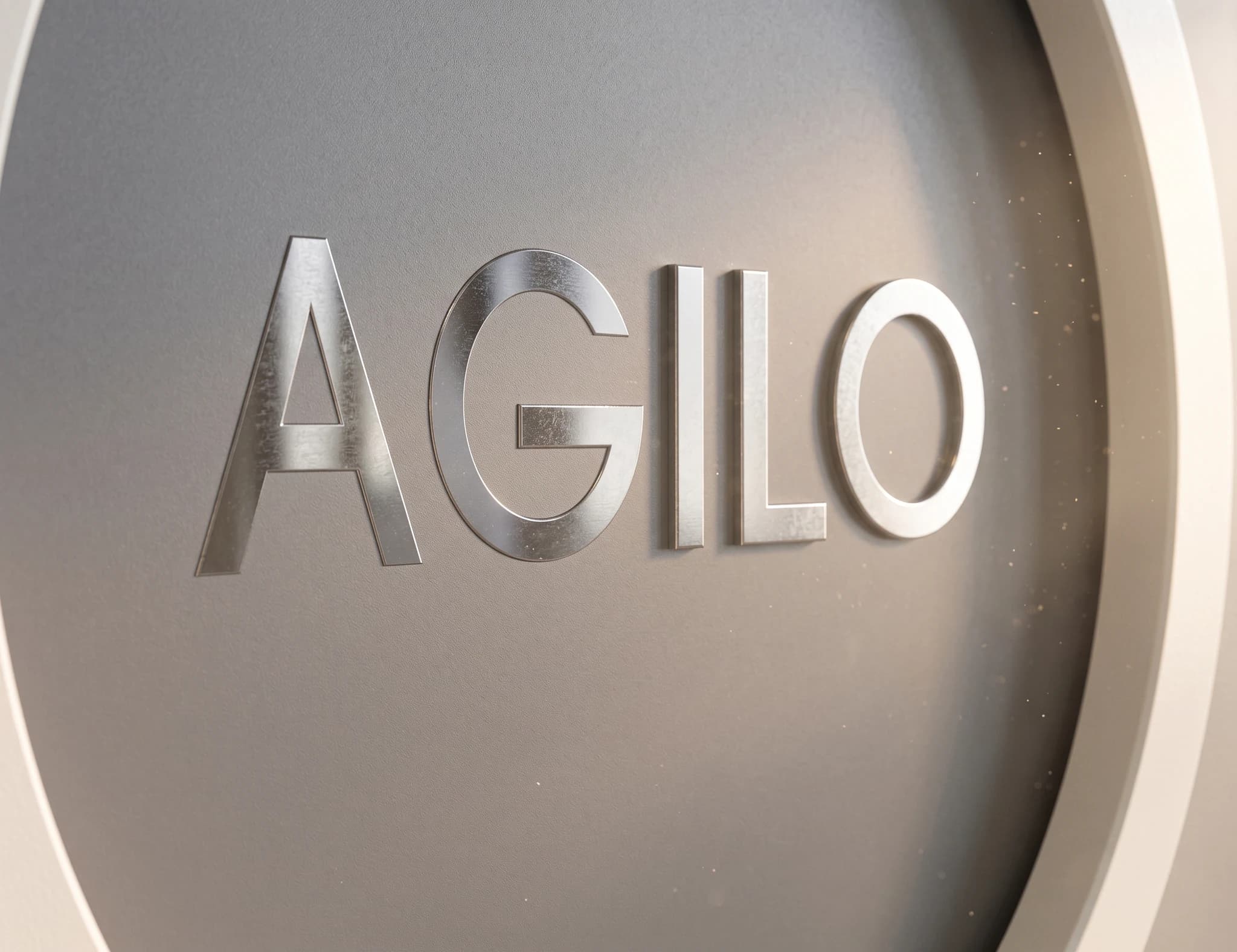 Företagslogotypen AGILO ingraverad på en grå vägg i en modern interiör.