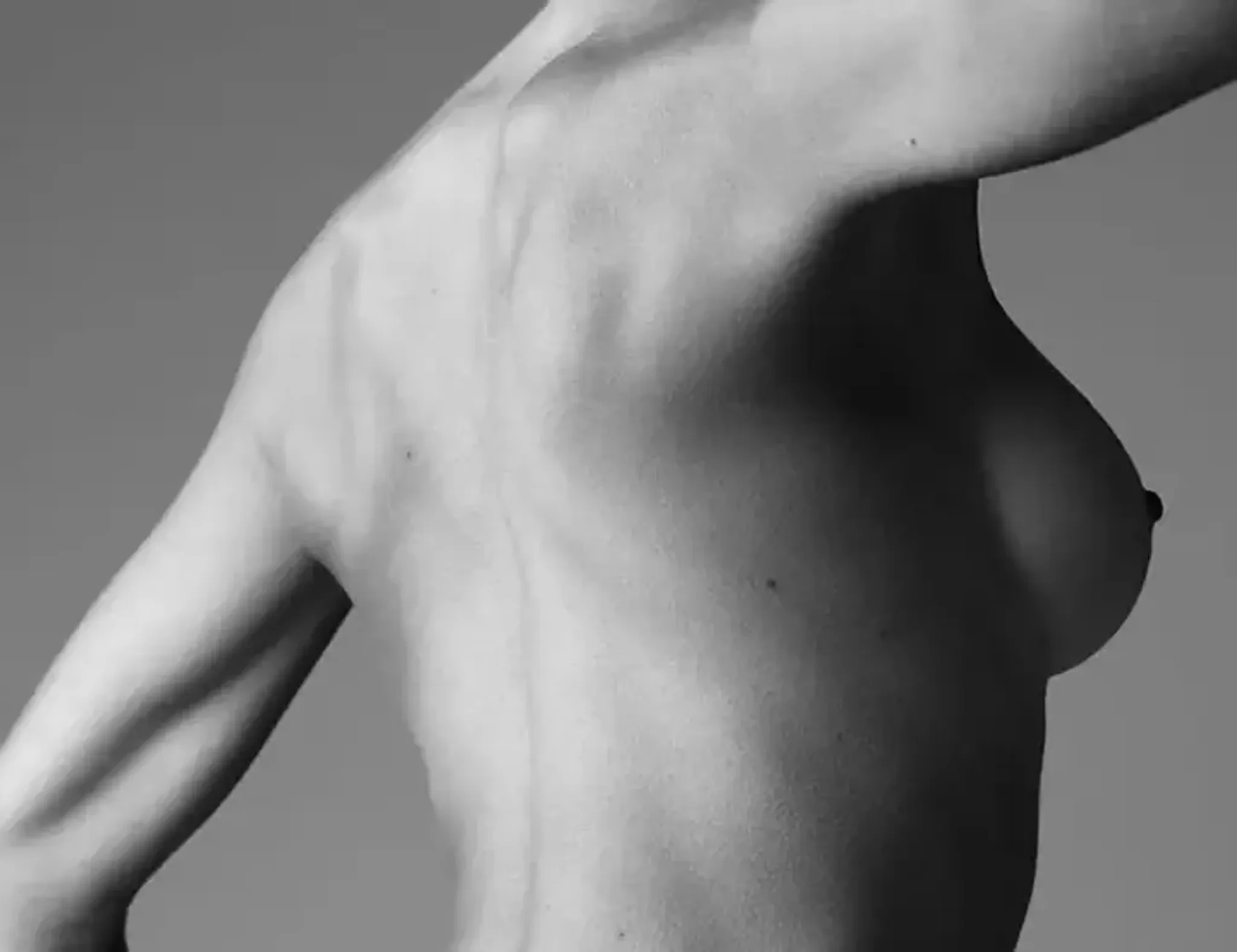 Kvinnans torso och arm i svartvitt, med fokus på skuggor och muskler