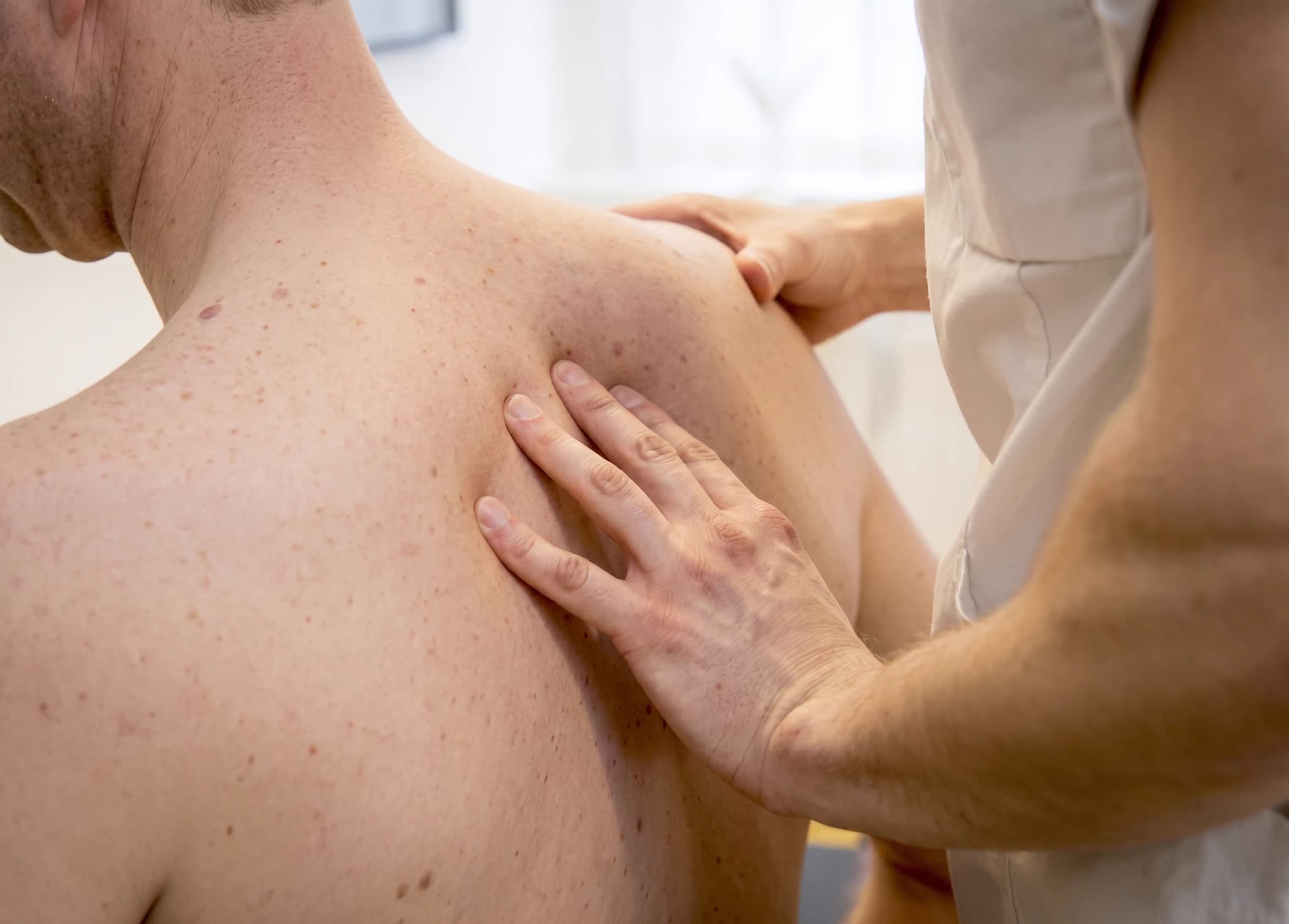 En terapeut masserar patientens axel och övre rygg.