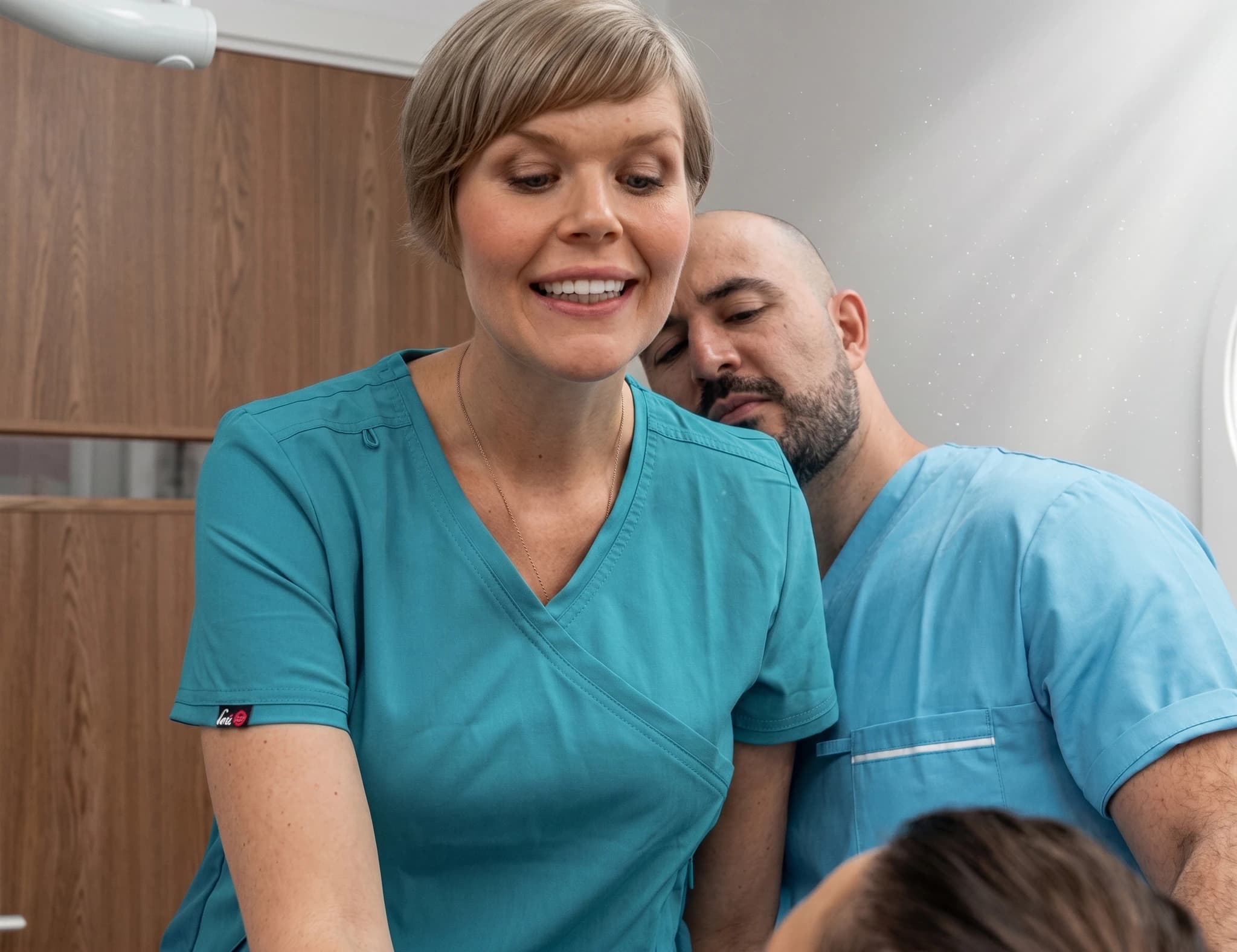Två sjukvårdspersonal, en kvinna och en man, som tittar på en patient.