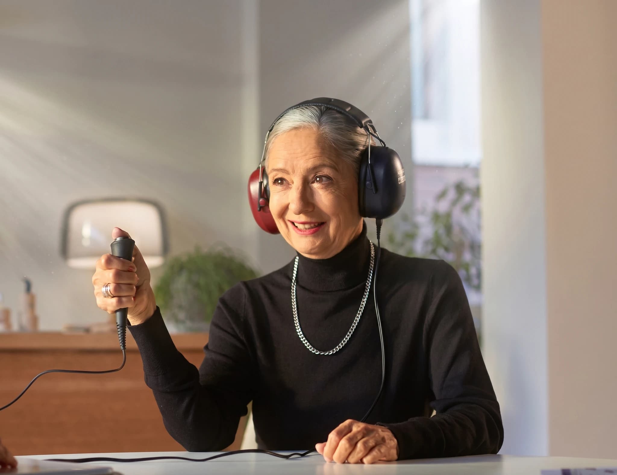 Äldre kvinna med hörlurar som använder en audiometer för ett hörseltest.