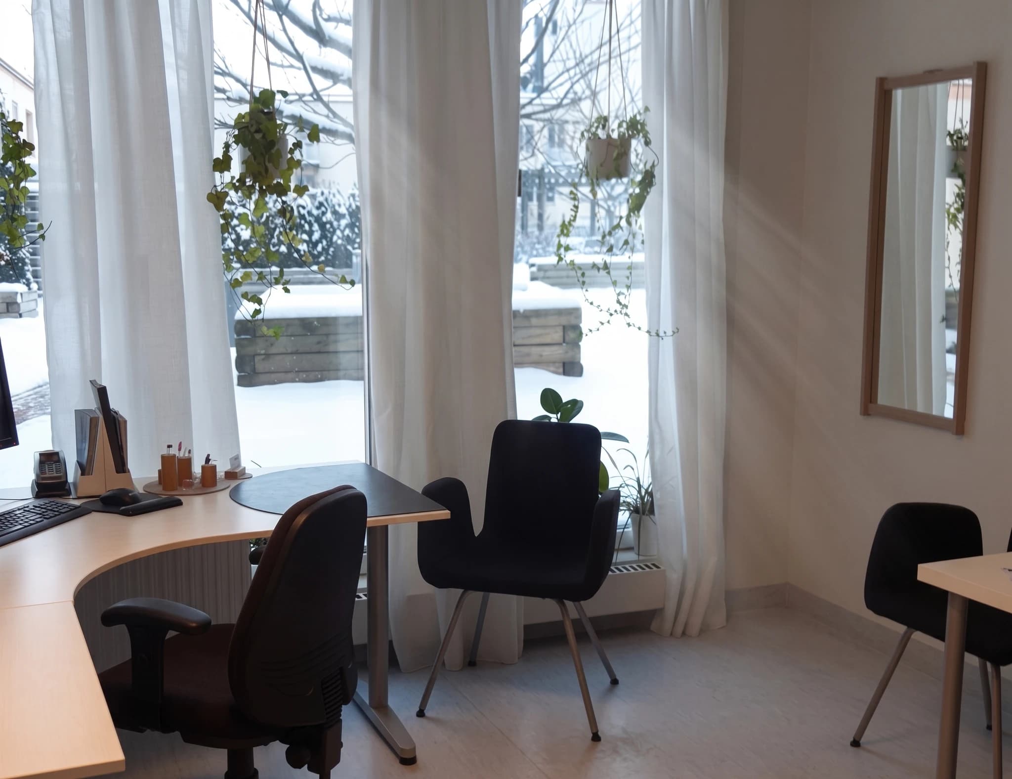 Ett kontor med skrivbord, stolar och en fönsterutsikt över snötäckt landskap.