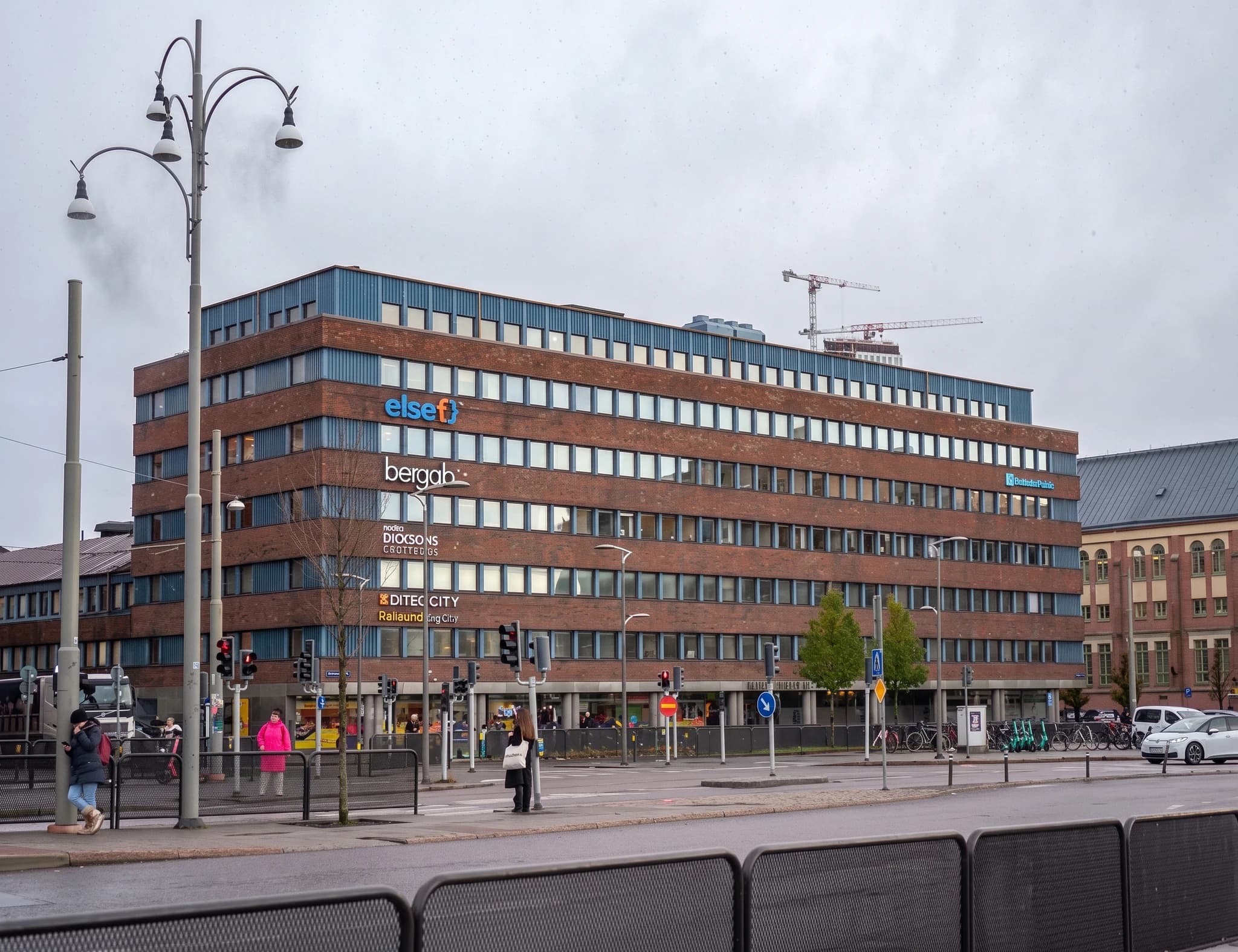 Modern tegelbyggnad med kontor och skyltar som 'else', 'bergab', 'DICKSONS STIFTELSER' och 'DITEC CITY'. Byggnaden har många fönster och en blå takkant.