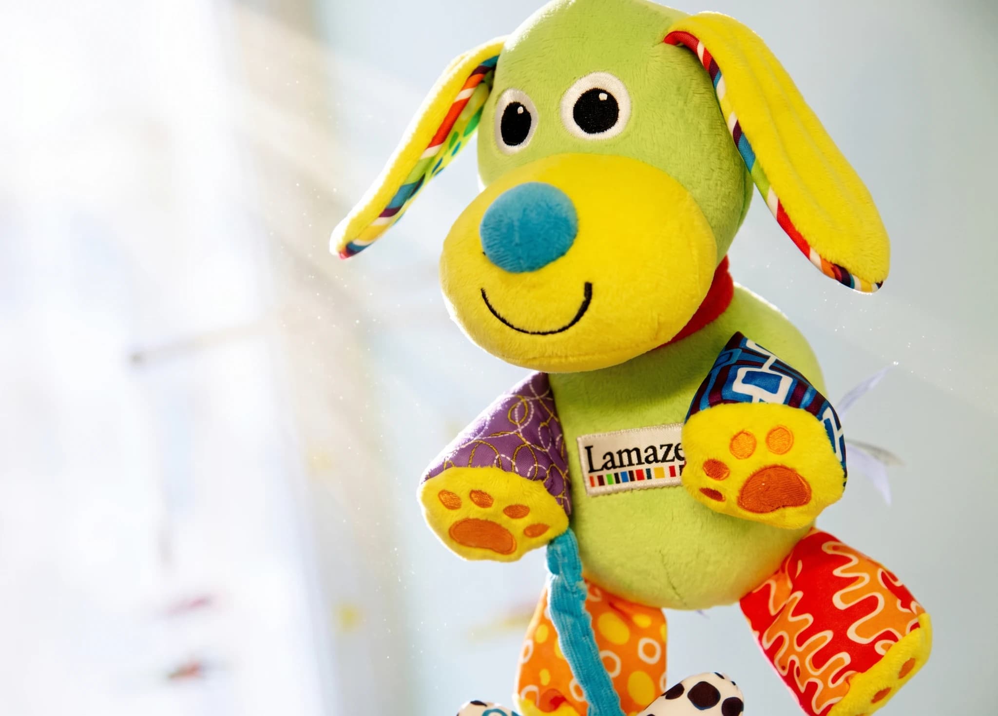 En färgglad Lamaze mjukdjurshund som hänger från en mobil.