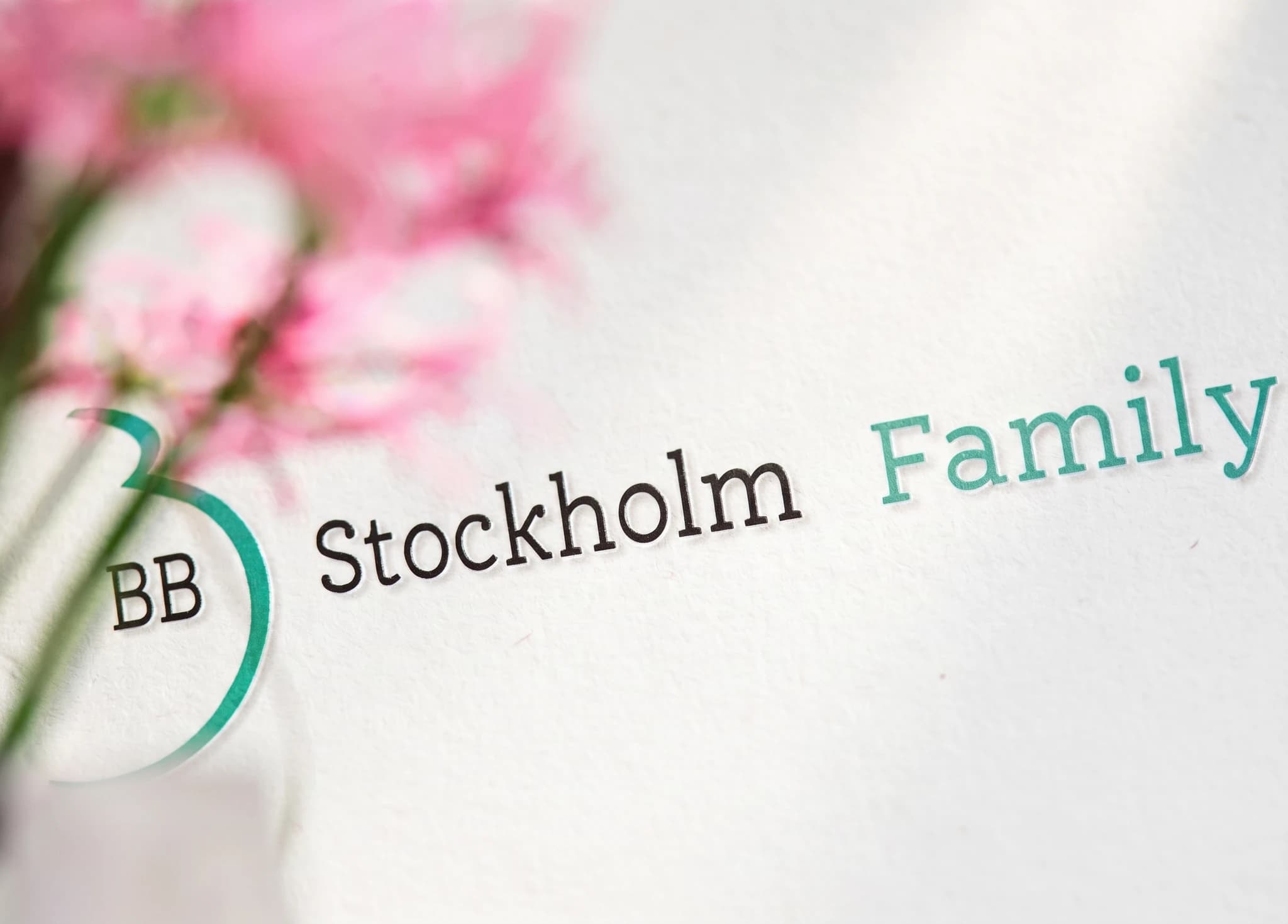 Text 'BB' i en cirkel bredvid 'Stockholm Family' med en suddig rosa blommig bakgrund.