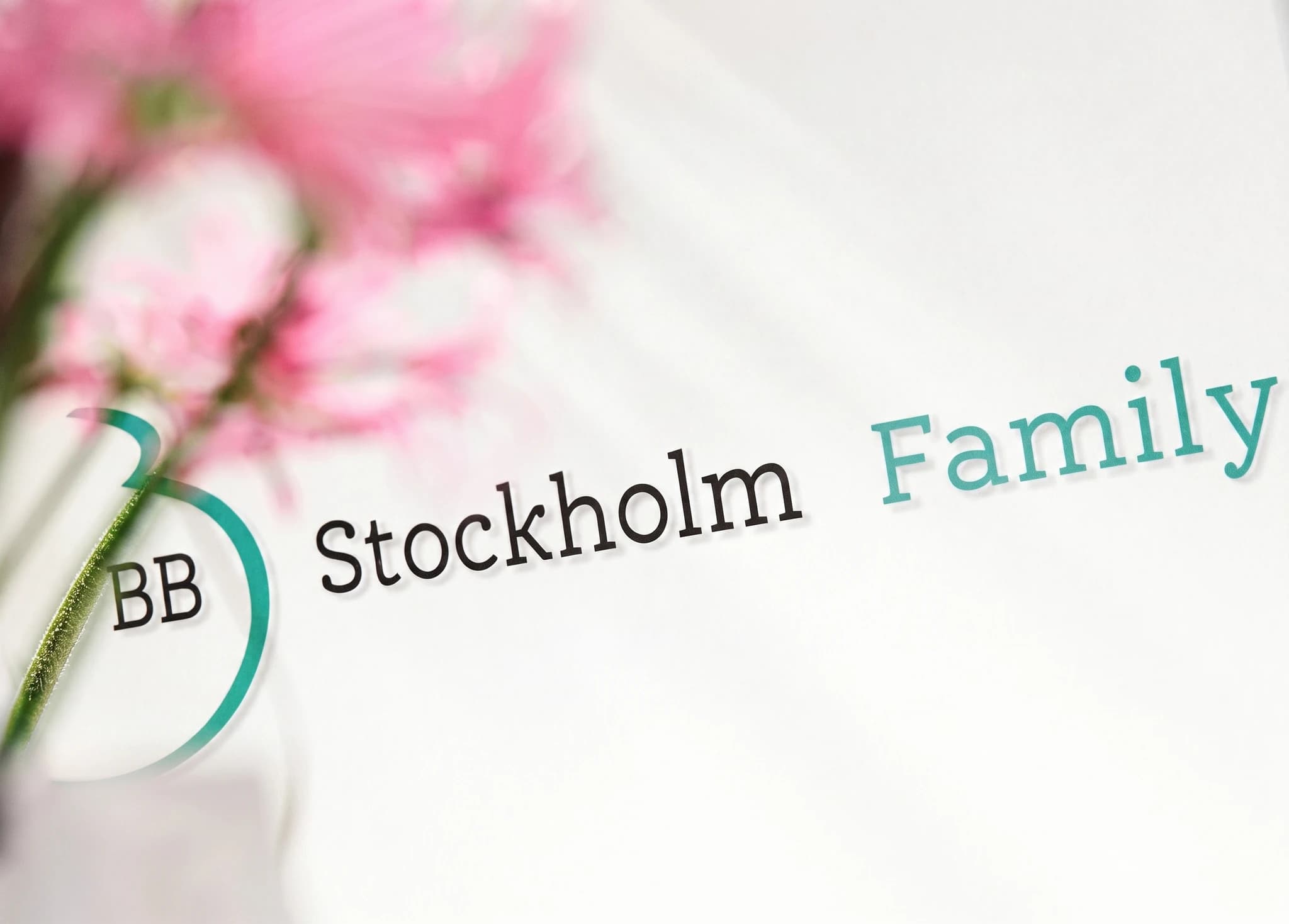 Grafisk bild med texten 'BB Stockholm Family' och en suddig bakgrund av rosa blommor.