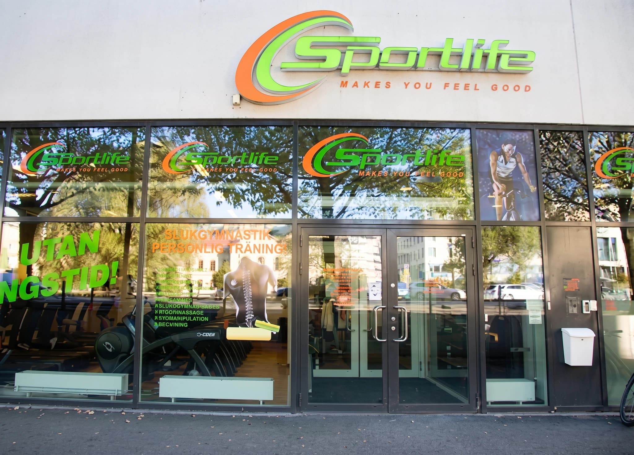 Fasaden av ett Sportlife gym med sin logotyp ovanför entrén och speglingar i fönstren.