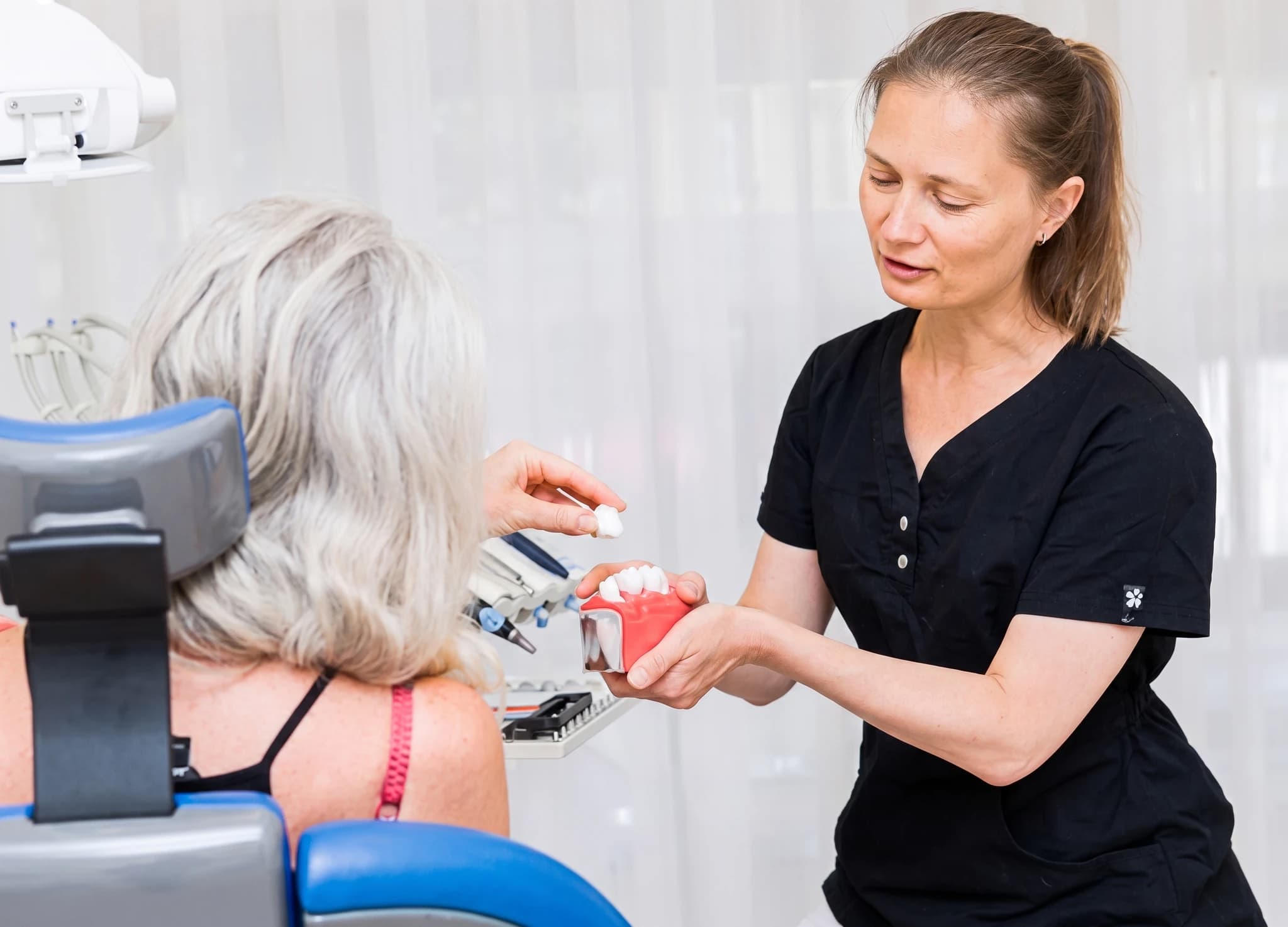 Tandläkare visar ett tandmodell för en patient i undersökningsrummet.
