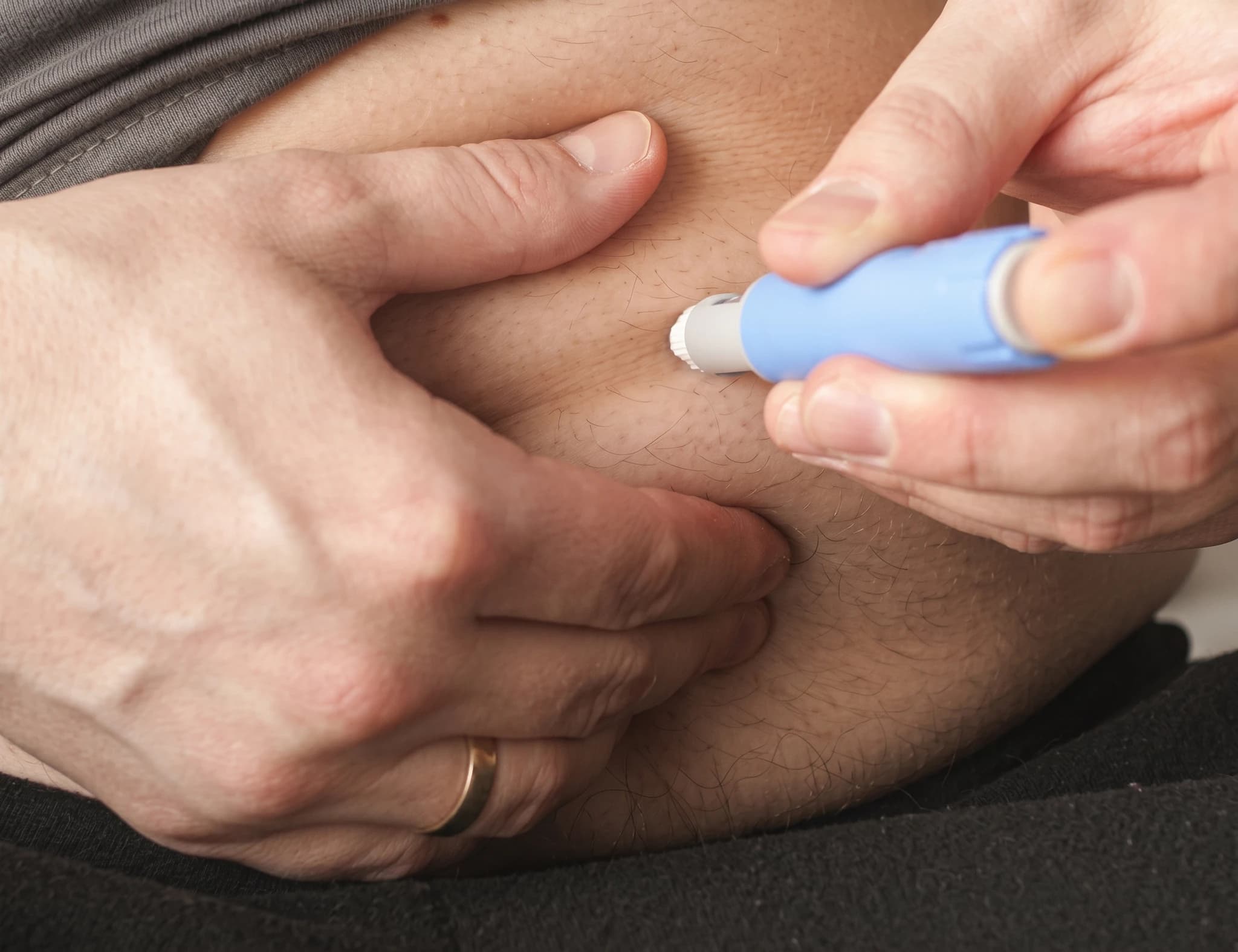 En person som injicerar insulin i buken med en injektionspenna.