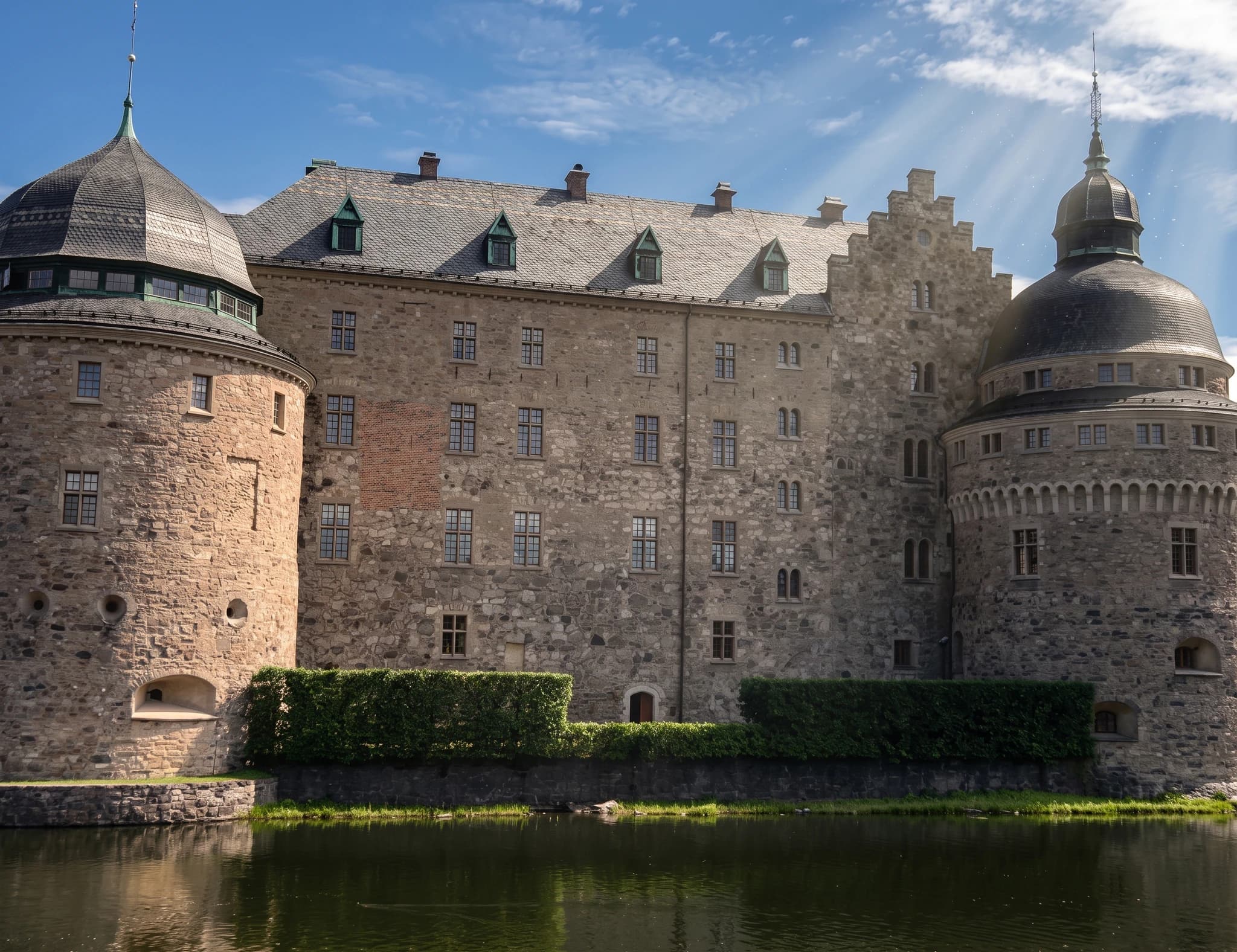 Exteriör av ett historiskt stenslott med vallgrav och himmel med moln.