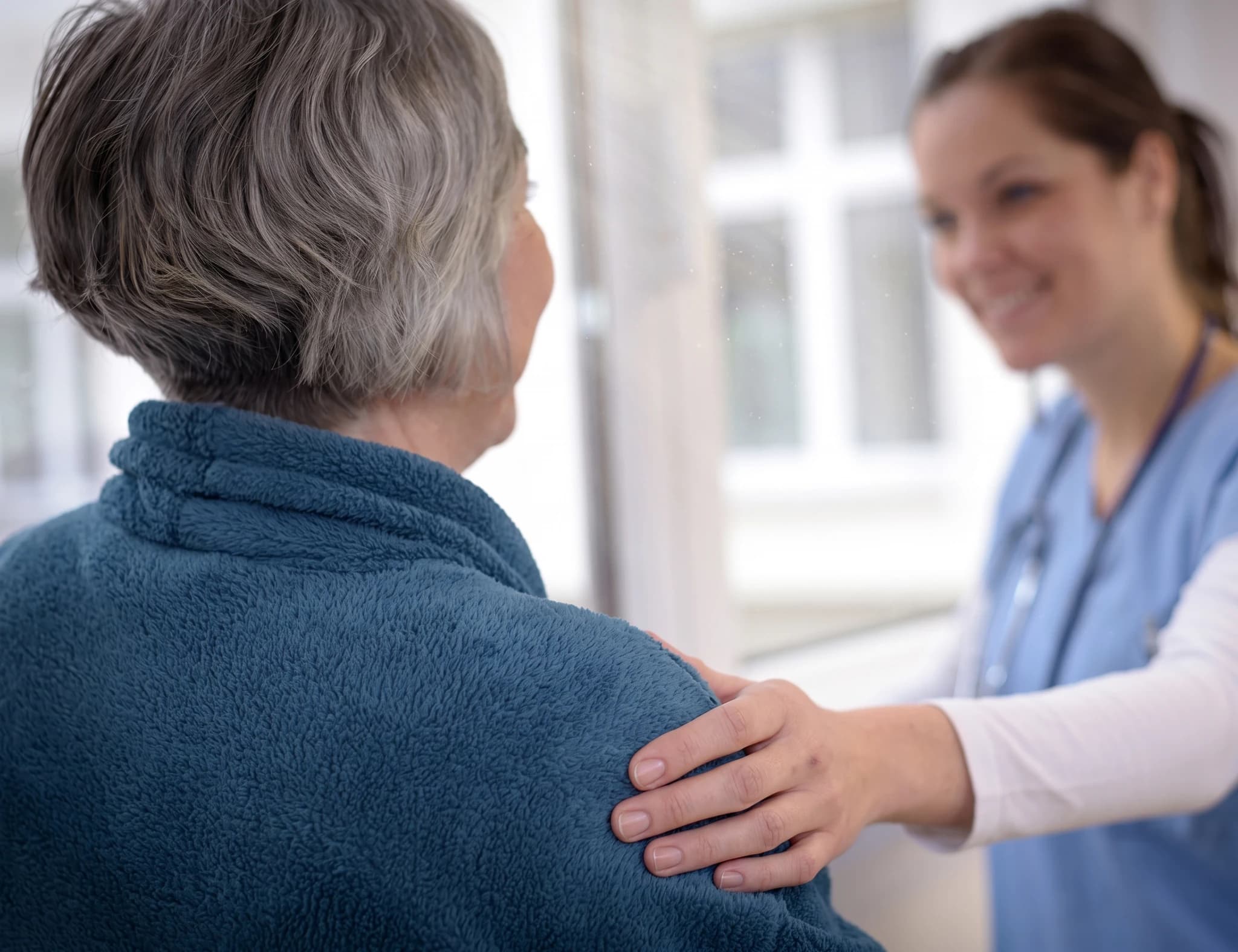 Sjuksköterska lägger en tröstande hand på en patients axel.