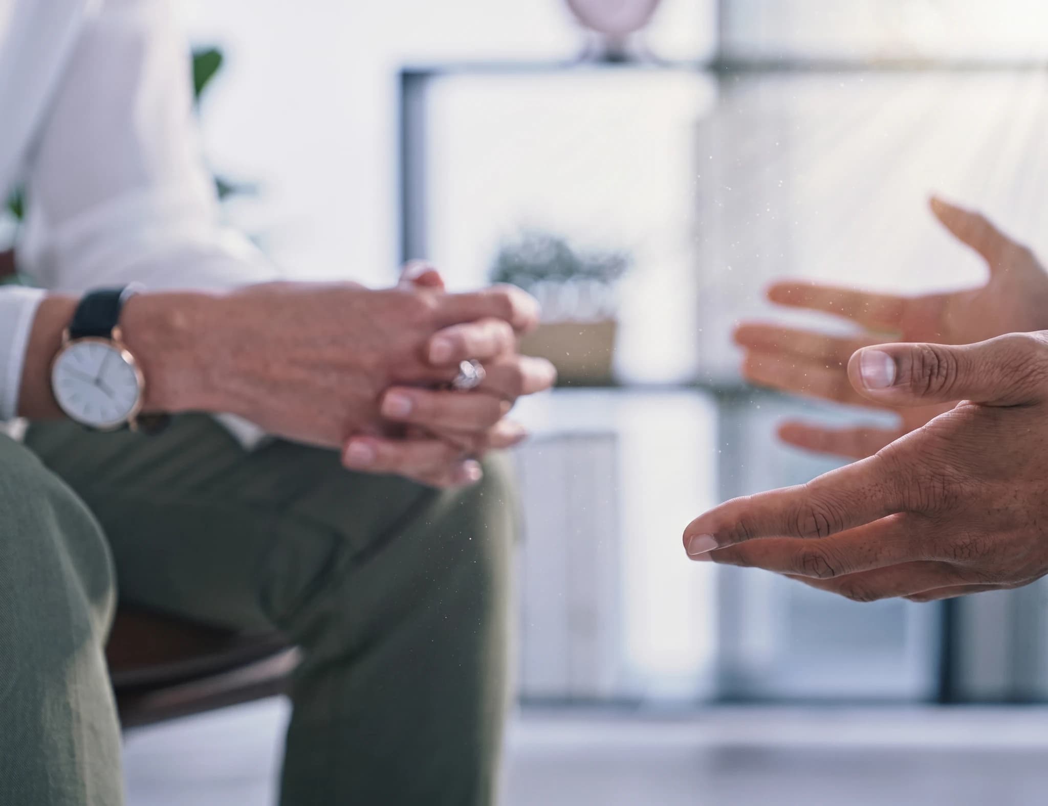 Två personer sitter och talar under en terapi- eller samtalssession, med fokus på händerna.