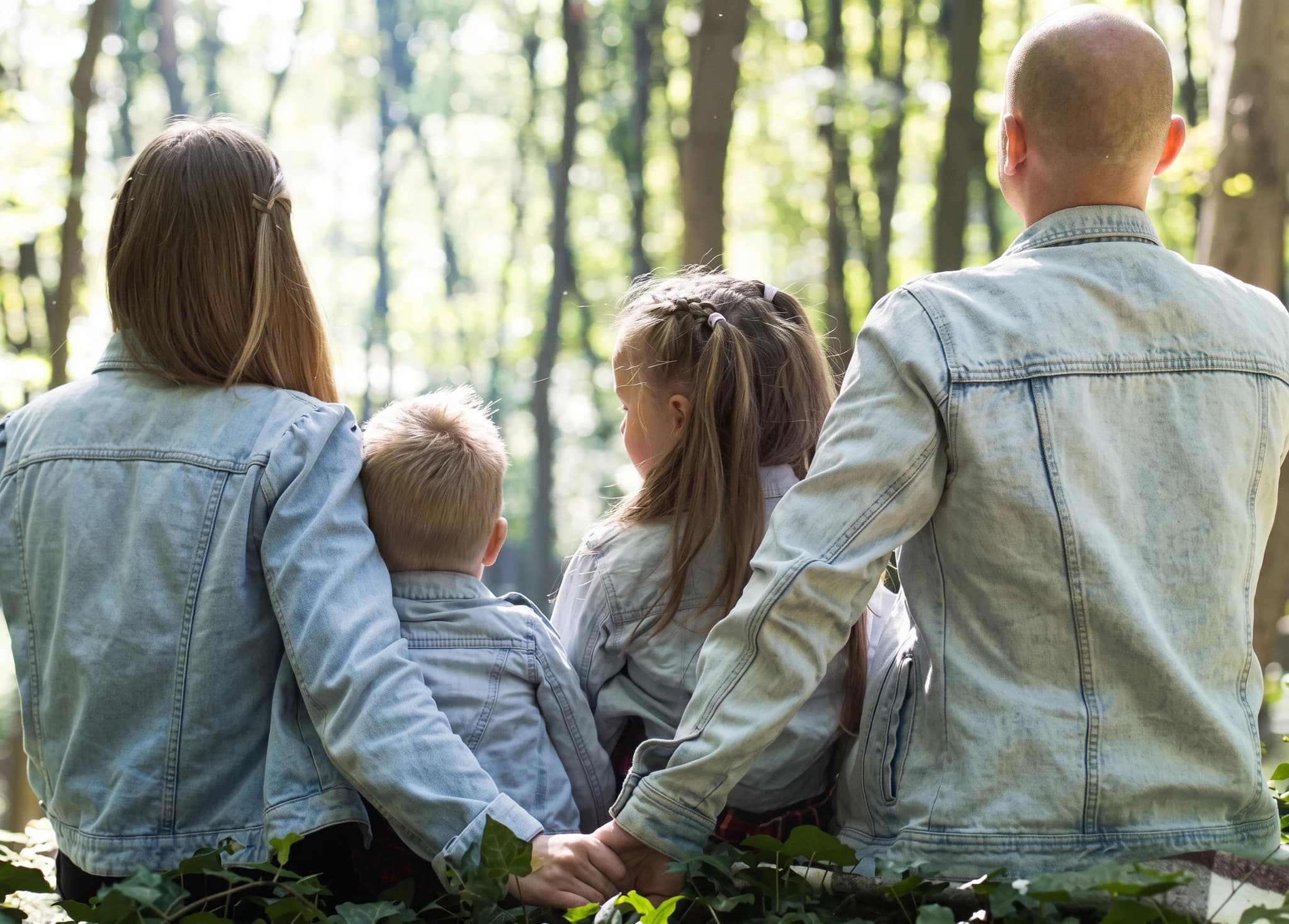 En familj sitter tillsammans i en skog och tittar bort