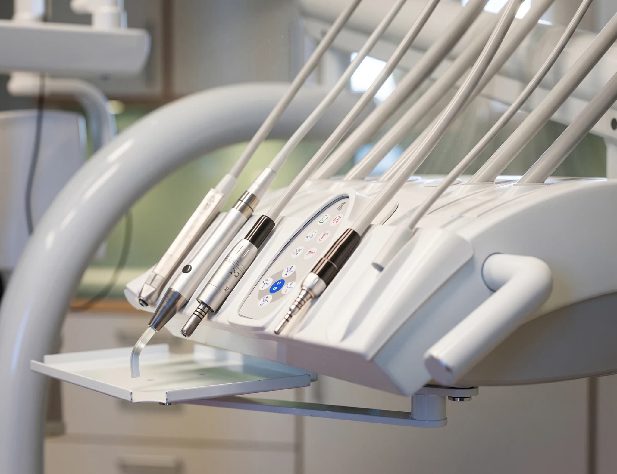 Närbild av en dentalborr och utrustningsställ med olika tandvårdsverktyg i en tandläkarmottagning.