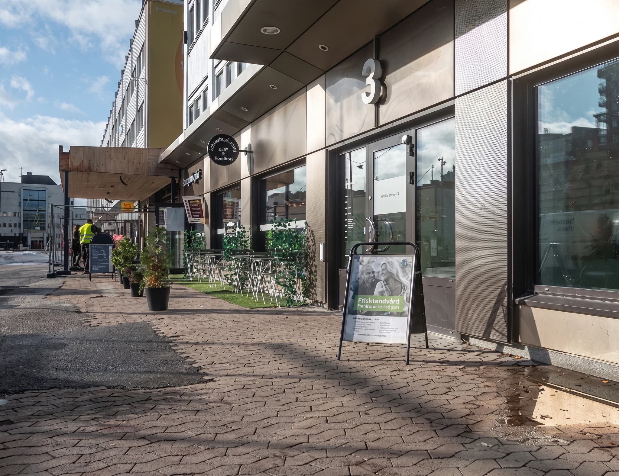 Byggnadens fasad med café-skylt och uteservering framför.