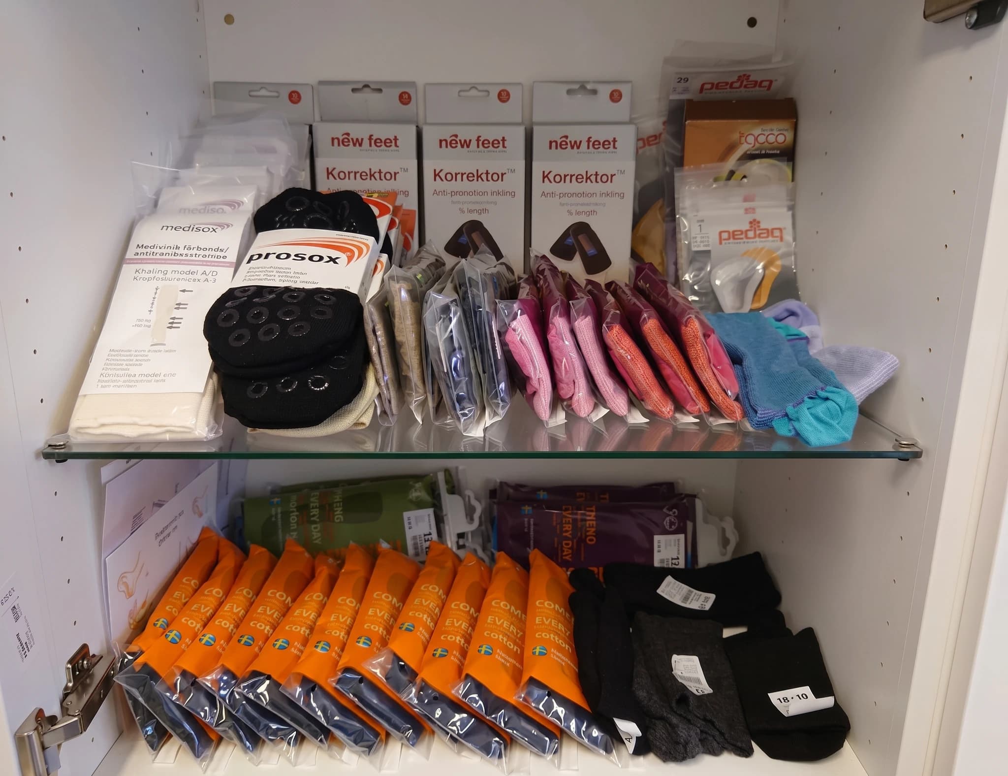 En hylla fylld med olika typer av strumpor och fotvårdsprodukter i förpackningar.