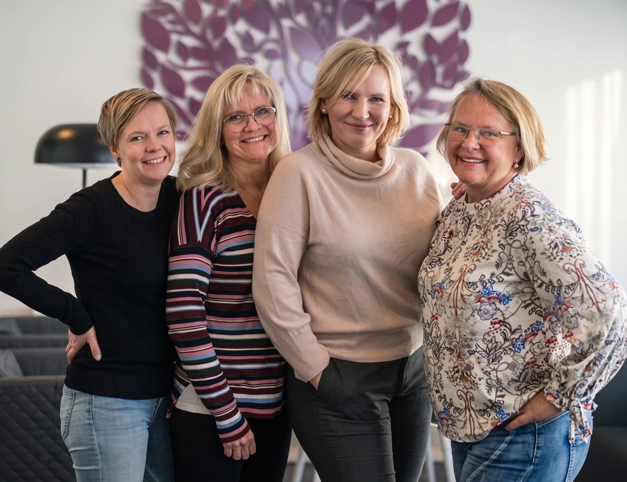 Fyra kvinnor som ler mot kameran i en inomhusmiljö.