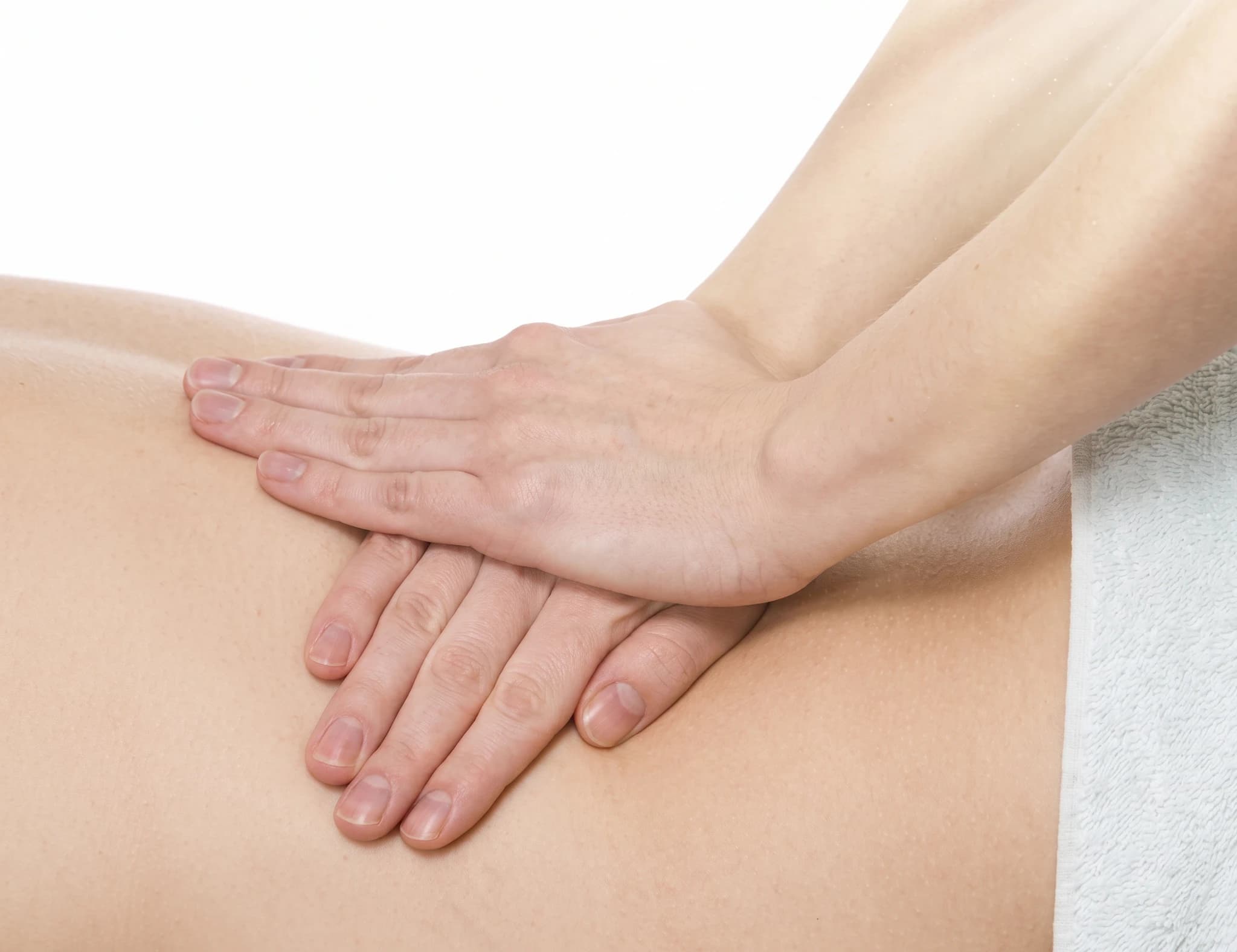 En terapeut utför en ryggmassage med händerna på en patients ländrygg.