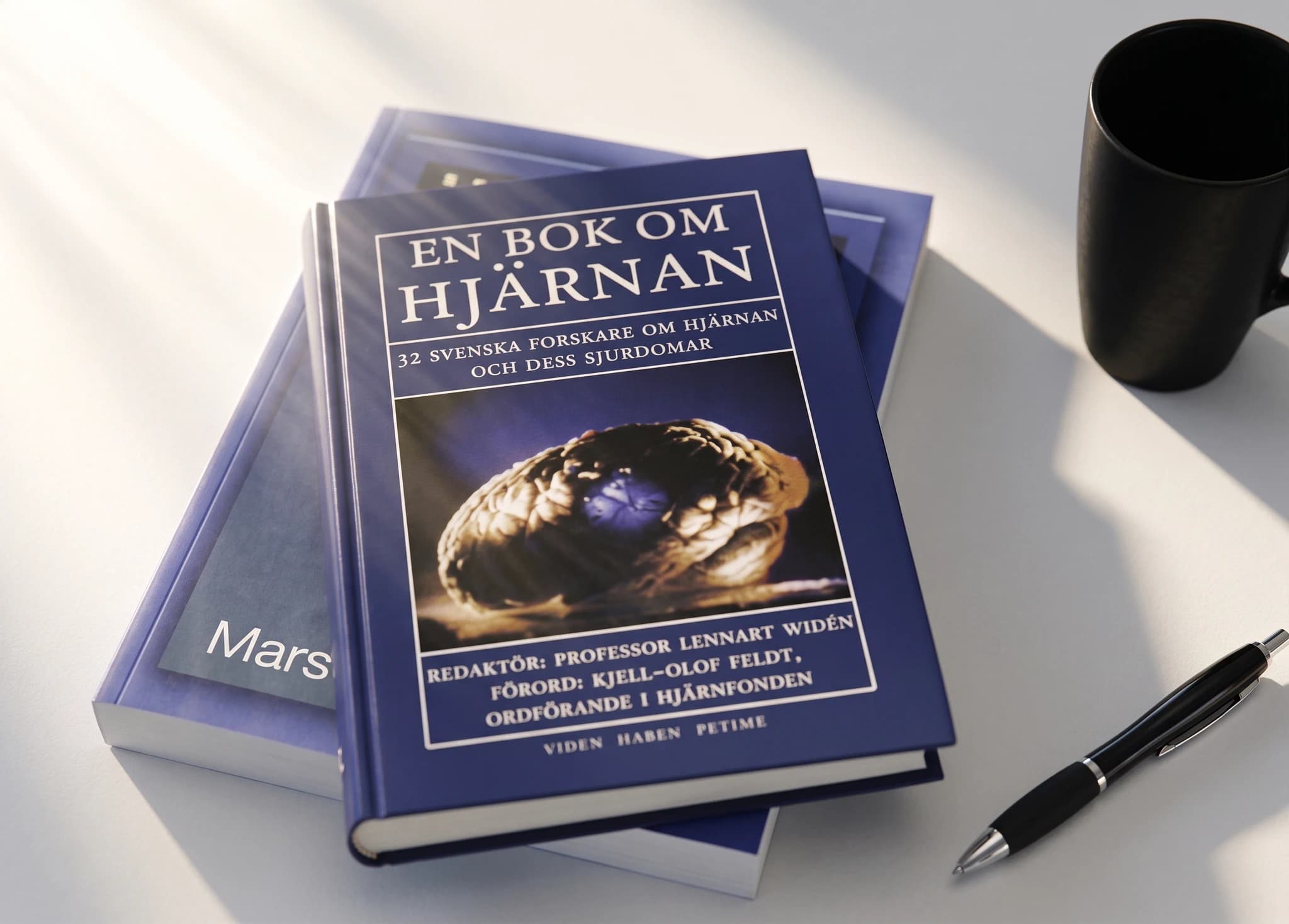 En stapel böcker med titeln "En bok om hjärnan" som handlar om hjärnan och dess sjukdomar, med en penna och en mugg bredvid.