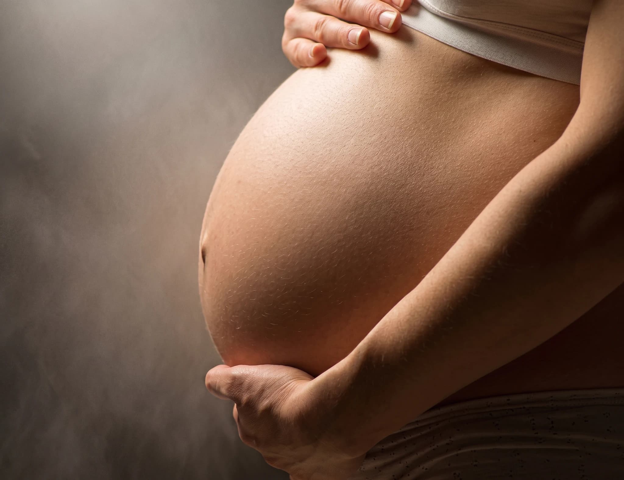Gravid mage med händer som håller om den.