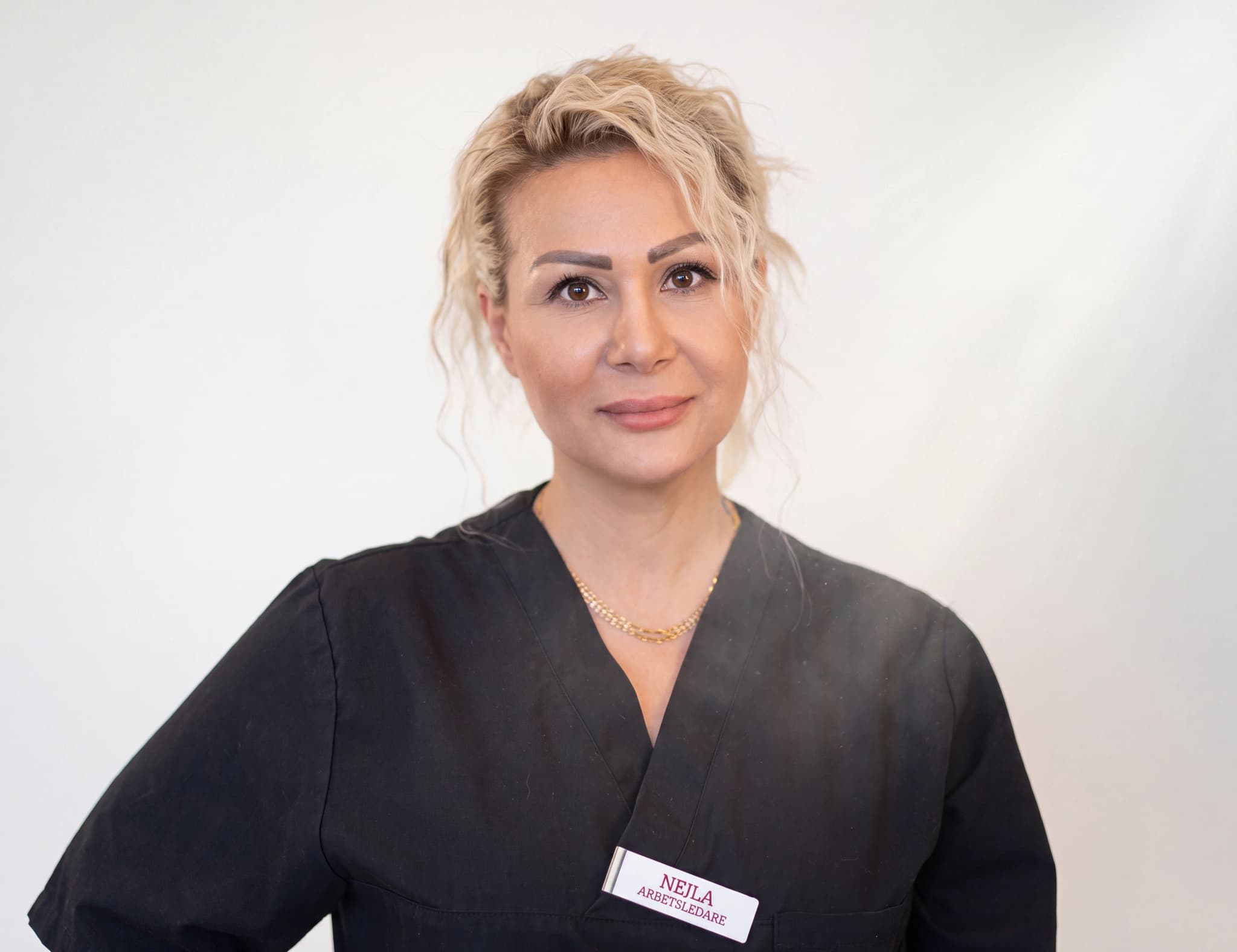 En professionell person i svarta arbetskläder med namnskylt med texten NEJLA ARBETSLEDARE.