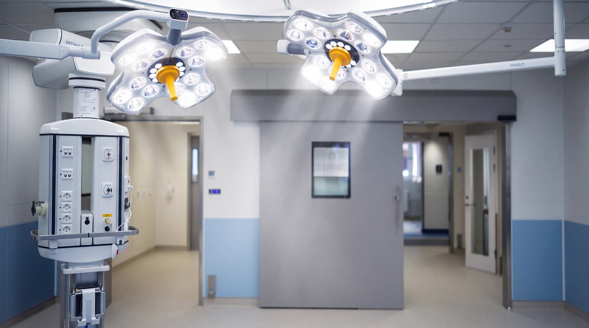 Moderna kirurgiska lampor och medicinsk utrustning, inklusive en infusionsställning, i ett sterilt operationsrum.