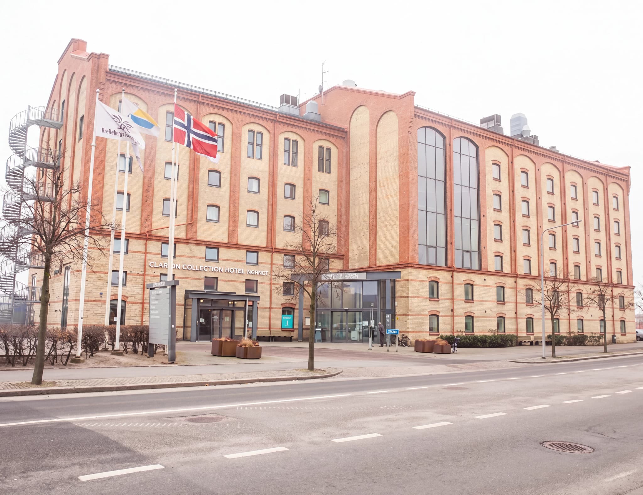 Exteriör av en stor tegelbyggnad med flera fönster och en ingång.